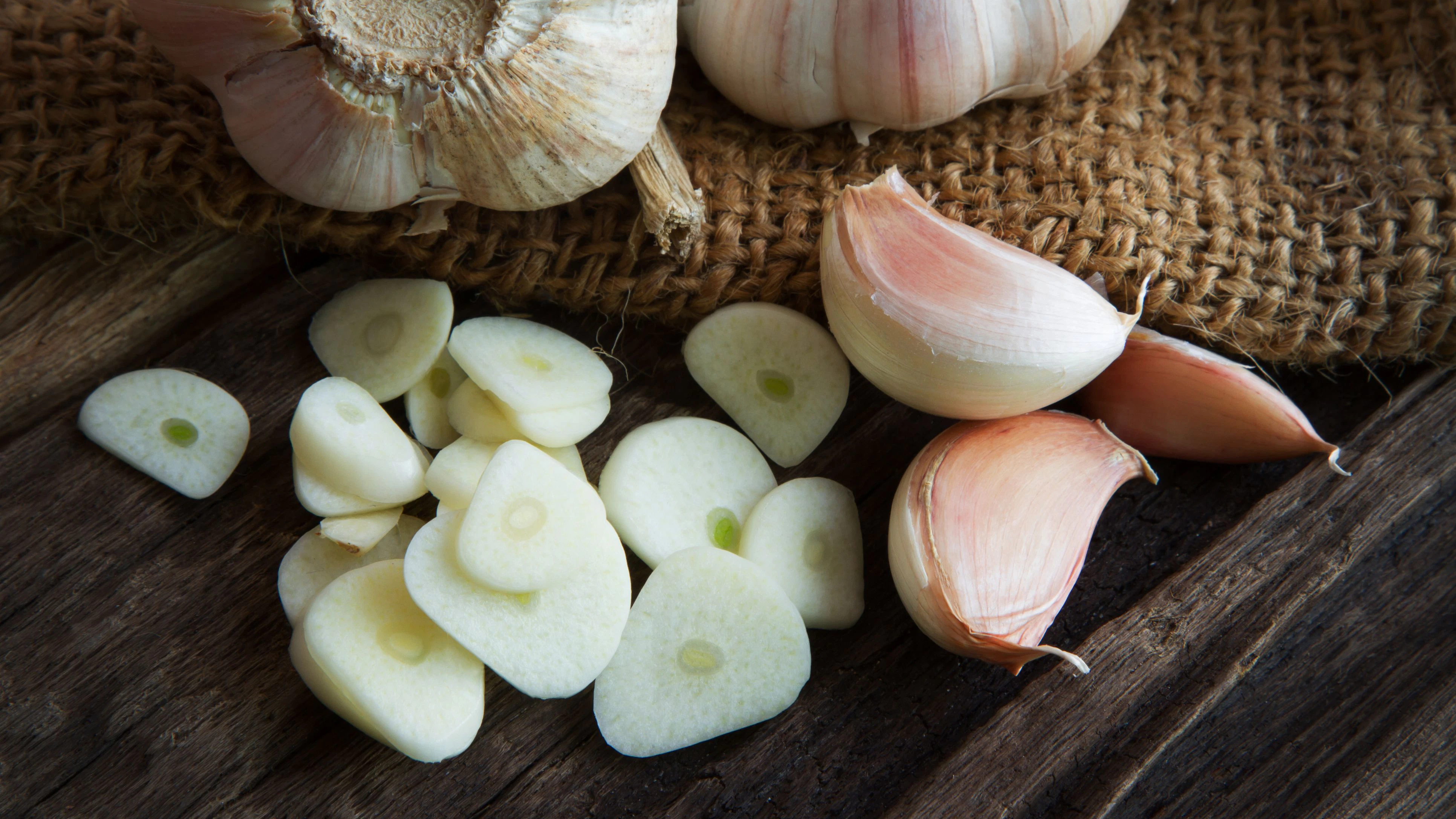 sliced garlic and garlic clove, garlic bulb on linen fabric and wooden table