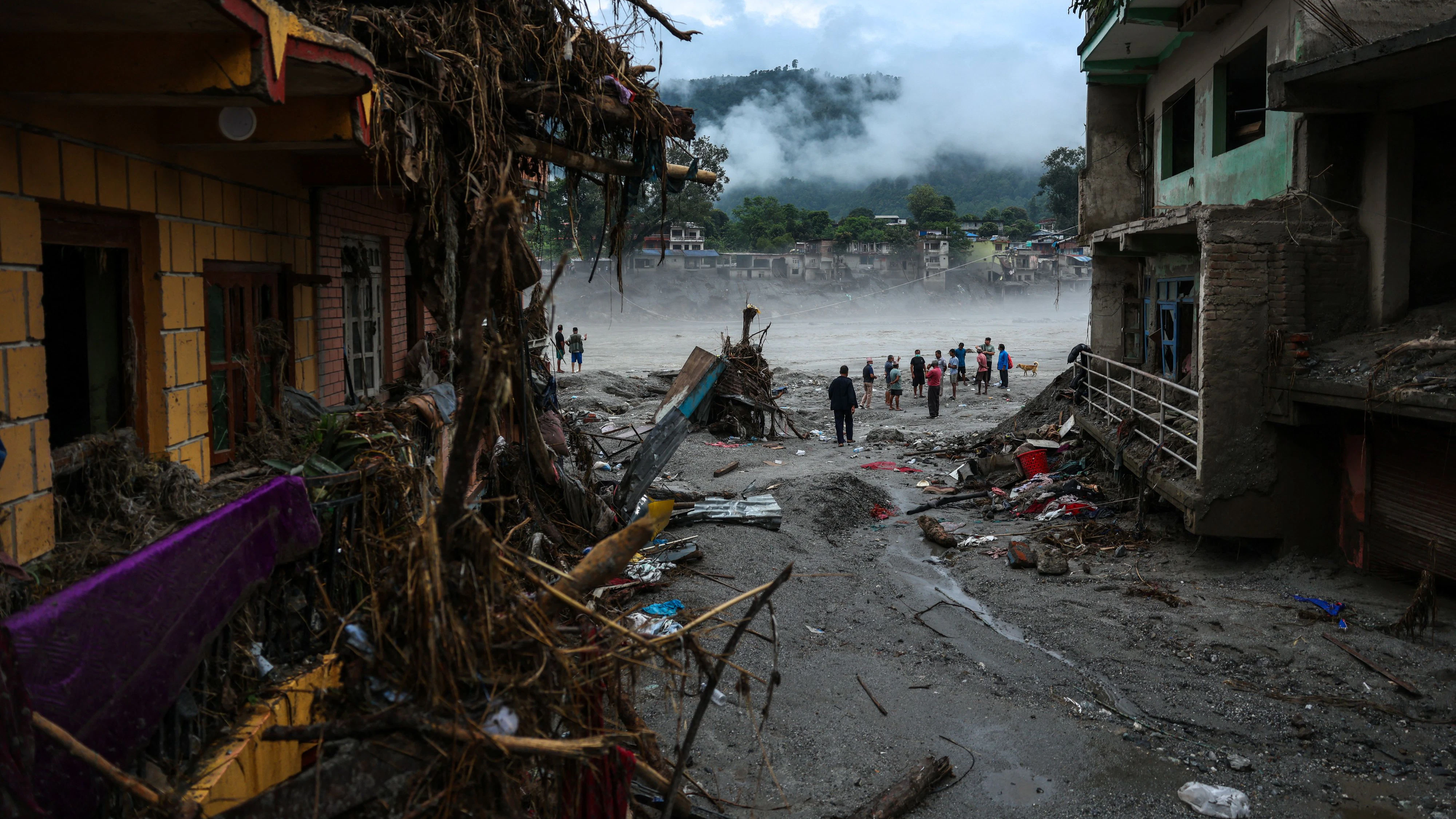 Menschen stehen neben beschädigten Gebäuden nach den verheerenden Sturzfluten und einem Schlammlawinenunglück in Devighat im Distrikt Nuwakot, Nepal, am 4. September 2026.