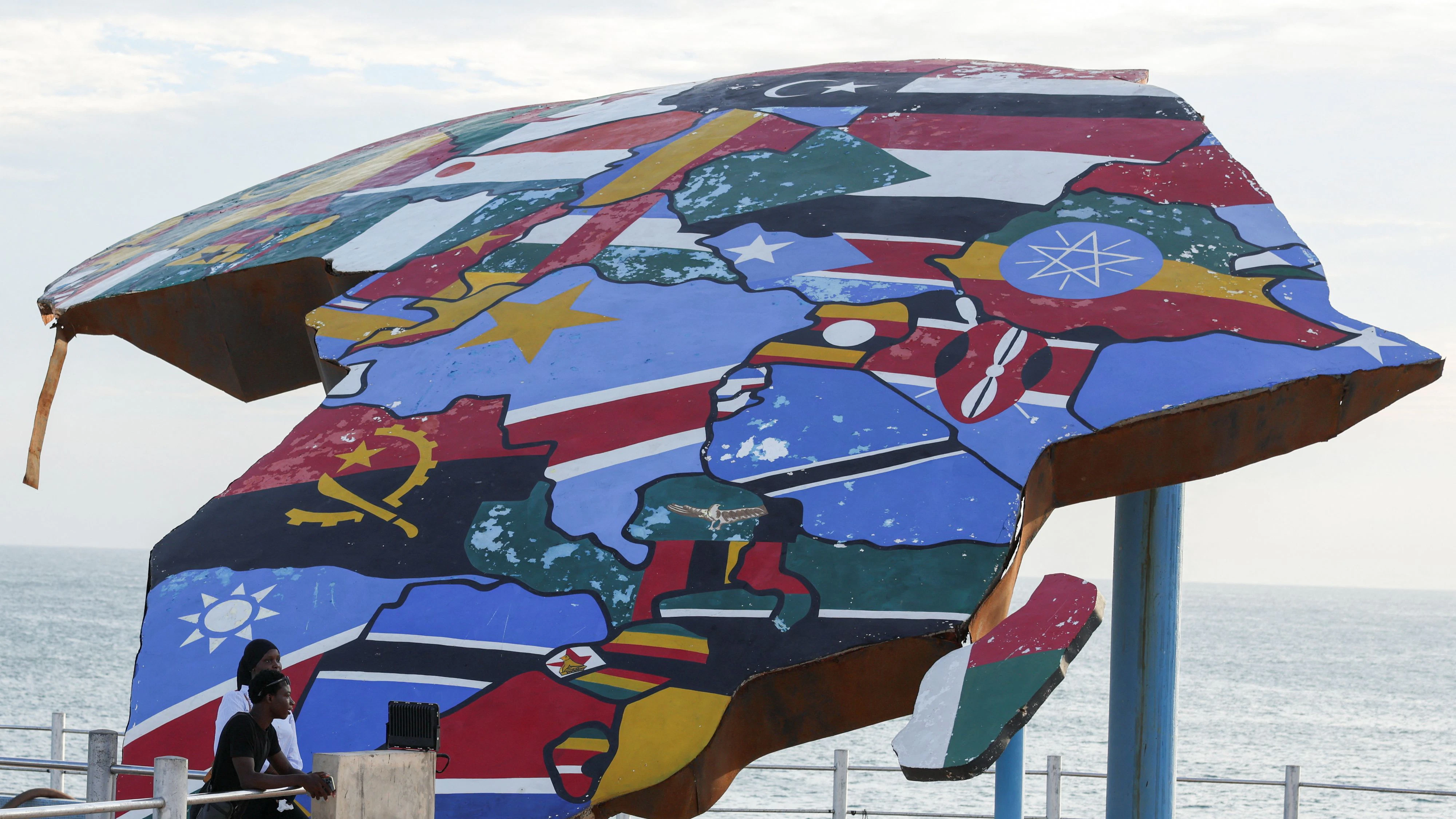 Menschen stehen neben einer Skulptur des afrikanischen Kontinents, die mit den Flaggen afrikanischer Staaten bemalt ist, auf der Place du Souvenir Africain in Dakar, Senegal, am 3. September 2026.