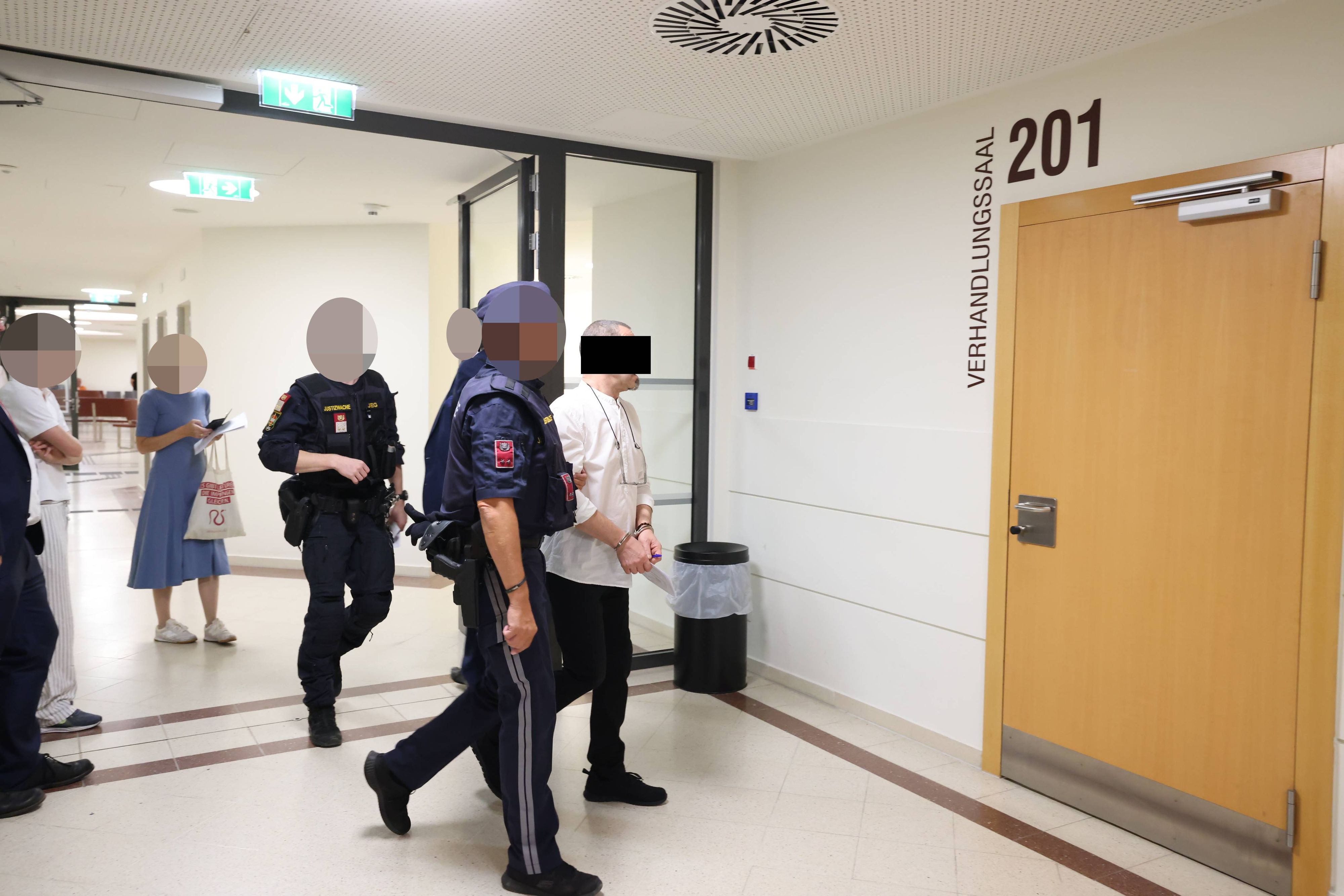 Der Angeklagte in Handschellen auf dem Weg in den Verhandlungssaal.
