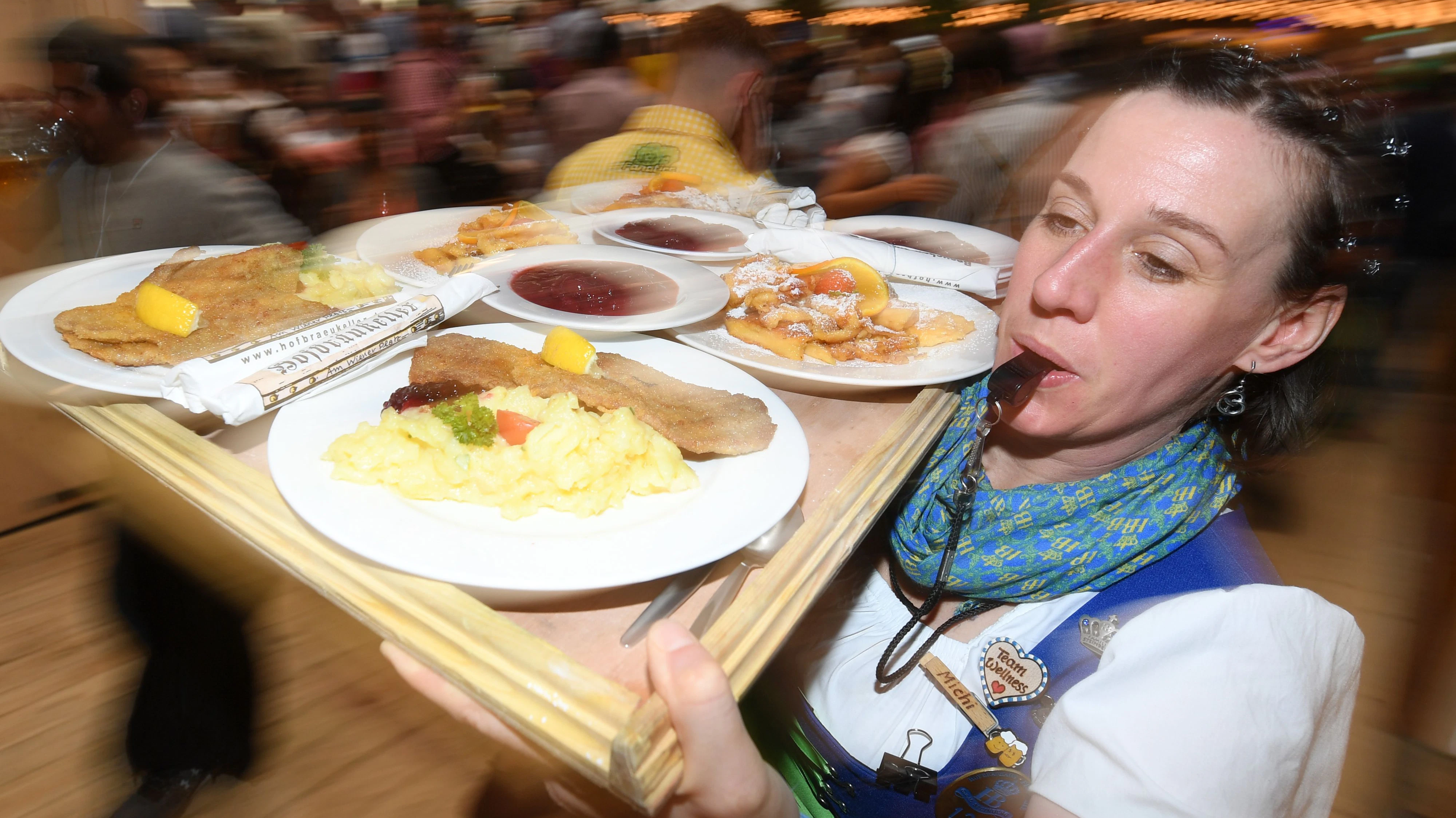A waitress carries a serving tray with schnitzels and Kaiserschmarrn, a shredded pancake dish, on the opening day of the Oktoberfest funfair in Munich, Germany, 16 September 2017. Photo: Tobias Hase/dpa
