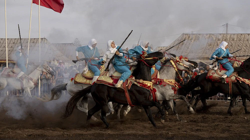 Title: Farīsāt: Gunpowder’s Daughters  Credit: © Chantal Pinzi, Panos Pictures  Caption: Noura attempts to control her horse after firing, the most dangerous part of the performance. Riders risk injury from gunpowder or falling and being trampled. Sidi Rahal, Morocco, 8 August 2025.  Story: Tbourida is a UNESCO-recognized Moroccan equestrian tradition dating back to the 16th century. Troupes gallop in unison, firing rifles in a choreographed performance of cavalry warfare. Historically excluded, female riders have fought for inclusion since Morocco’s 2004 family code reforms strengthened women’s legal rights. Today, seven all-female troupes now ride among some 300. These farīsāt (horsewomen) bear significant personal costs, funding their own horses, costumes, and gunpowder permits. Their perseverance stands as a powerful claim to women’s rightful place in Moroccan cultural heritage. 