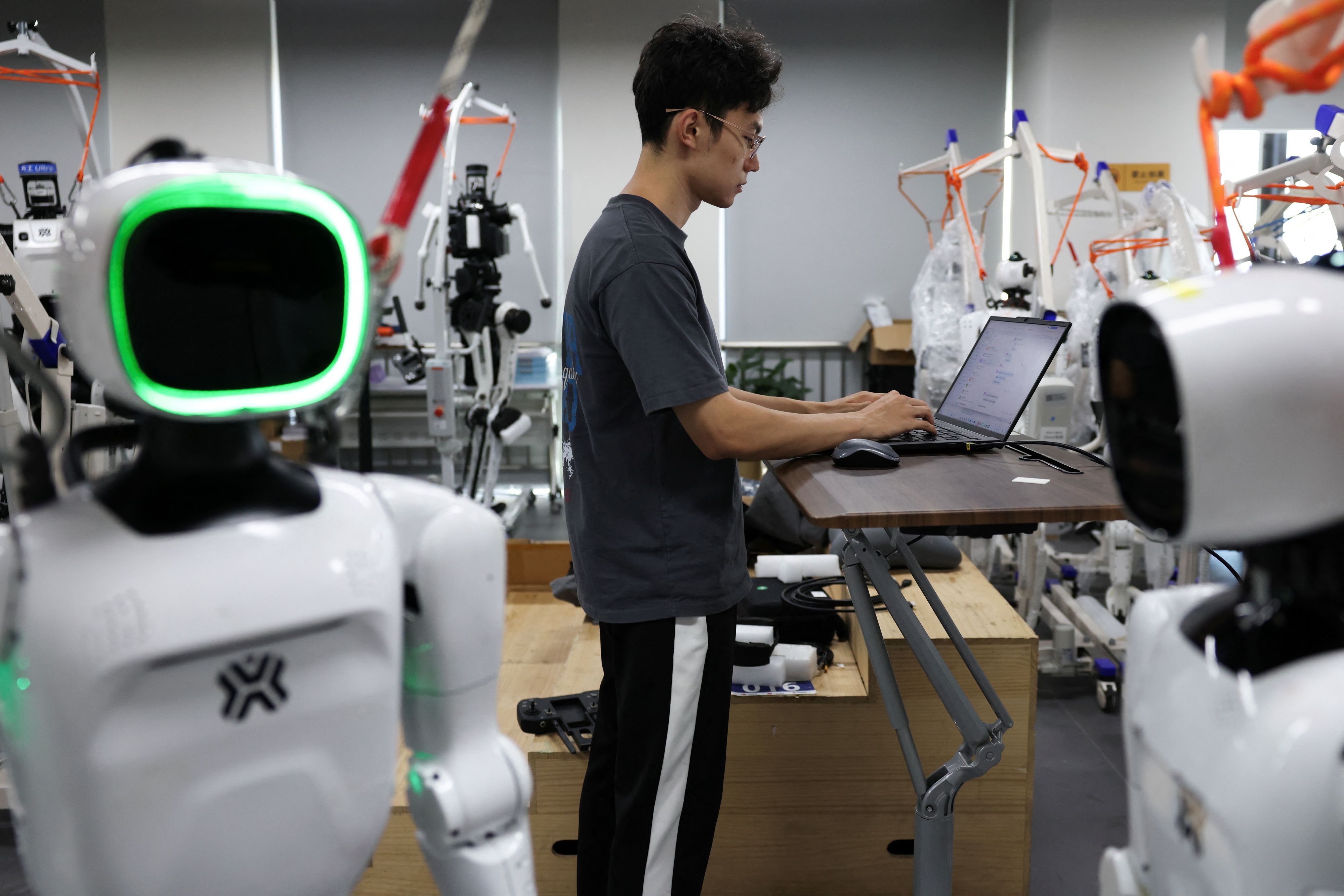 Ein Ingenieur arbeitet inmitten der humanoiden Roboter „Tiangong Omni“ und „Tiangong Ultra“ im Forschungs- und Testbereich des Beijing Humanoid Robot Innovation Center – auch bekannt als X-Humanoid – in Peking, China, am 4. September 2026.