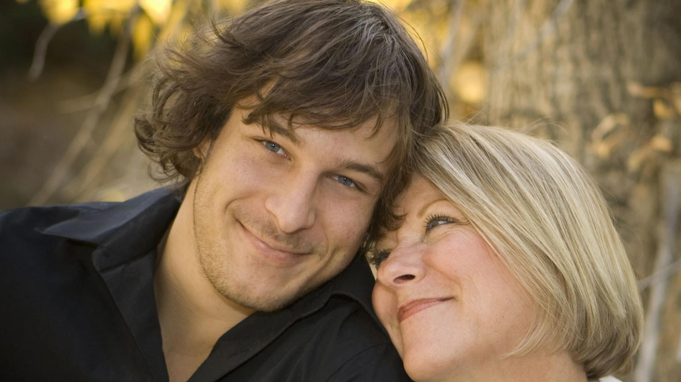 Portrait of a mother and her son. Mom is looking at her son, he's smiling at the camera.