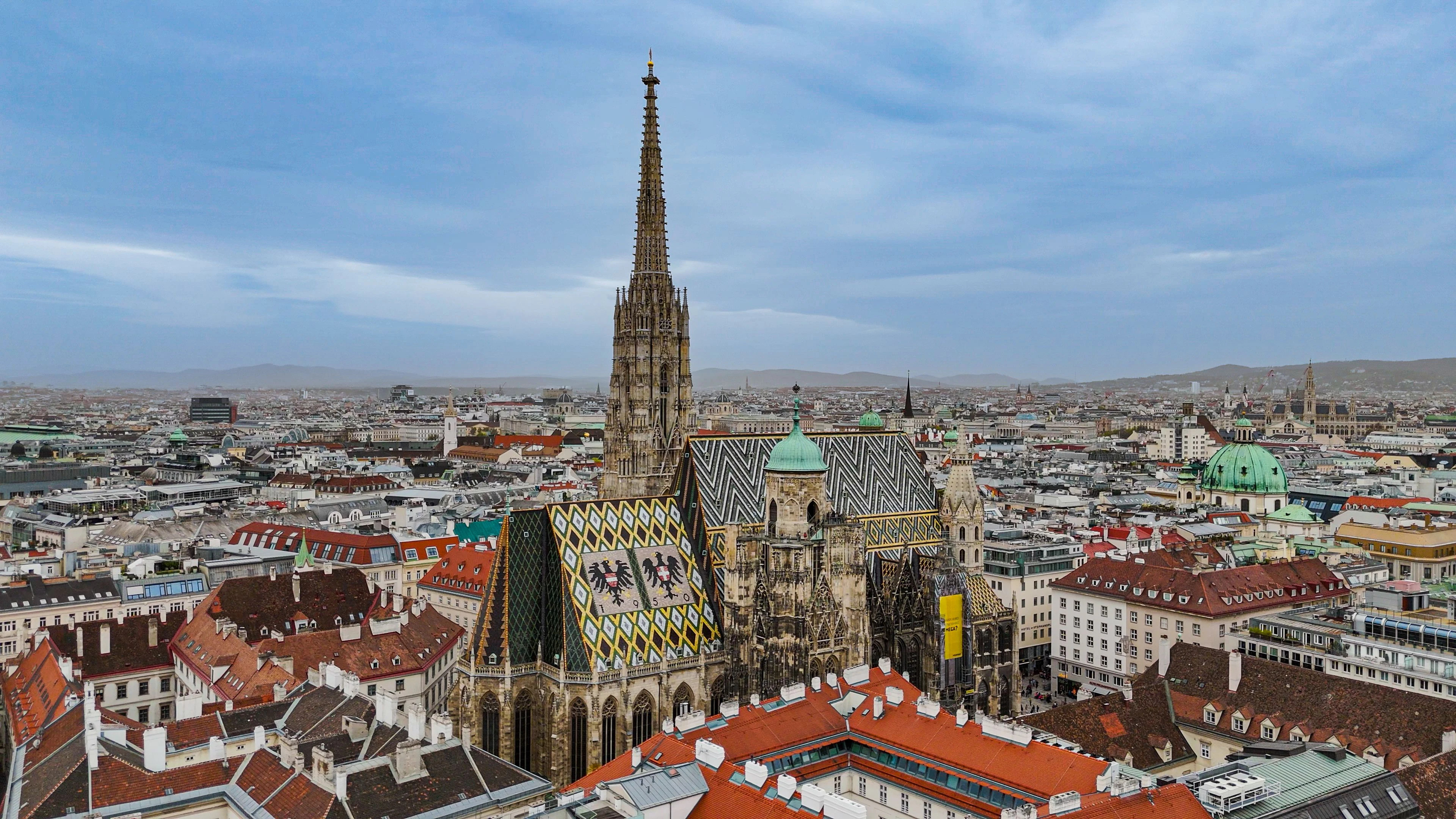 St. Stephen's Cathedral in Vienna, Aerial View of St. Stephen's Cathedral, Iconic St. Stephen's Cathedral Rooftop, Vienna's Historic St. Stephen's Cathedral, Architectural Beauty of St. Stephen's Cathedral  This aerial videos showcases the magnificent St. Stephen's Cathedral in Vienna, highlighting its colorful tiled rooftop and intricate Gothic architecture. The cathedral is a symbol of Vienna's rich history and cultural heritage, attracting visitors from around the world.