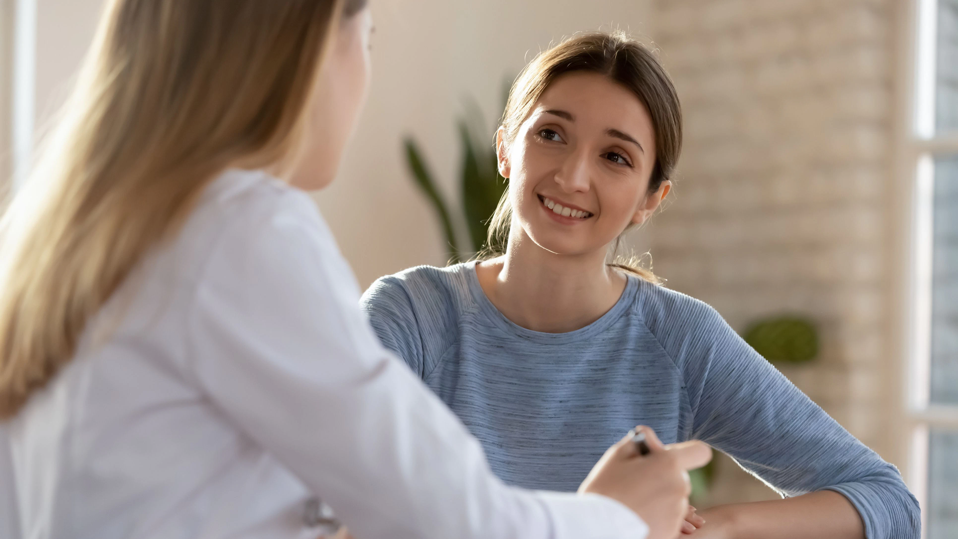 Lächelnde Frau besucht eine Community Nurse, die sie berät, glückliche zufriedene junge Kundengespräche besprechen Sozialangebote.