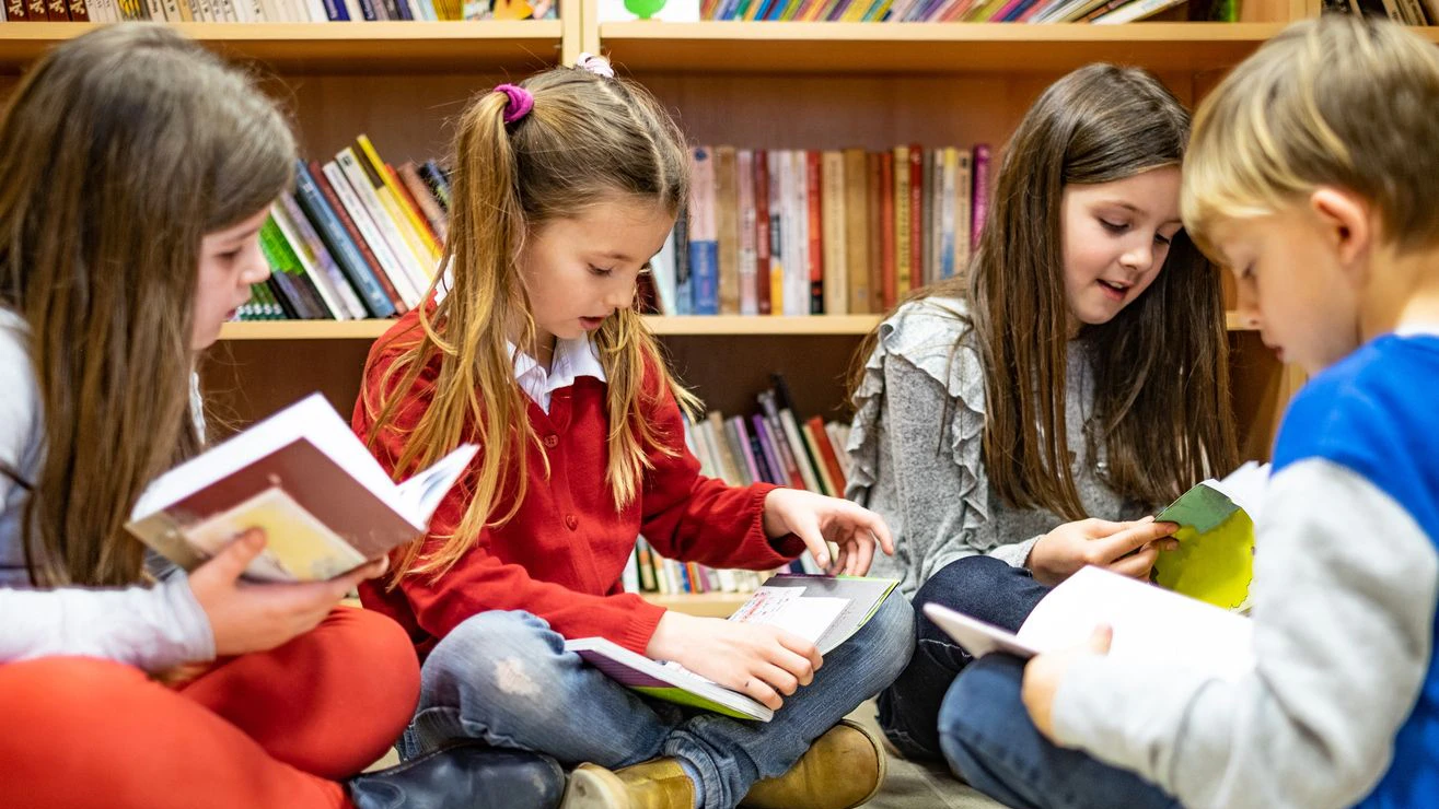 Group of children sitting on library floor and searching a books