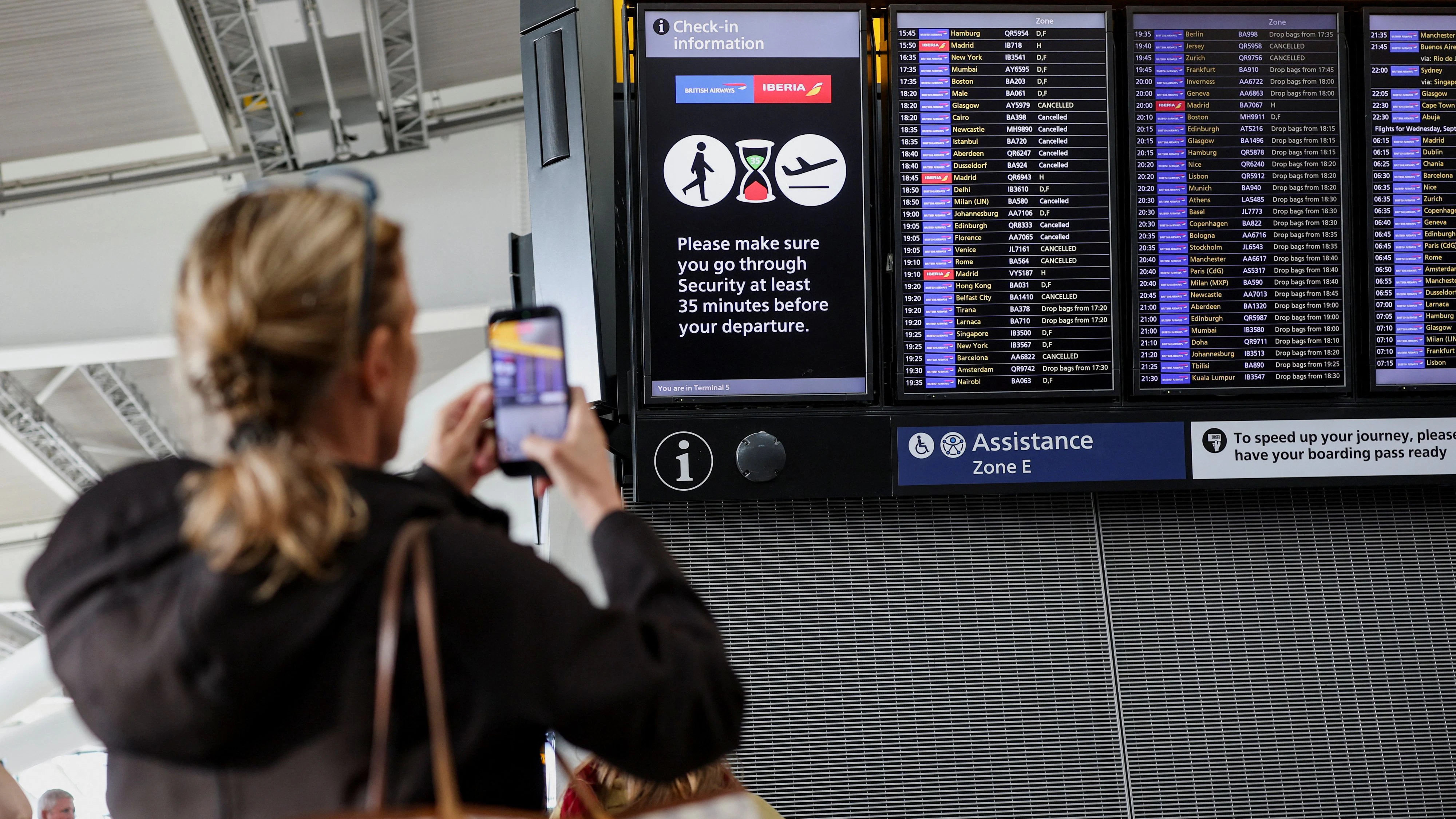 A passenger records a departure board displaying cancelled flights at Heathrow Airport's Terminal 5 in London, Britain, September 8, 2026. Some departing flights at major British airports were disrupted on Tuesday after air traffic control provider NATS experienced a technical issue, with Heathrow, Gatwick, Manchester and Stansted among the airports affected by restrictions and delays. REUTERS/Isabel Infantes