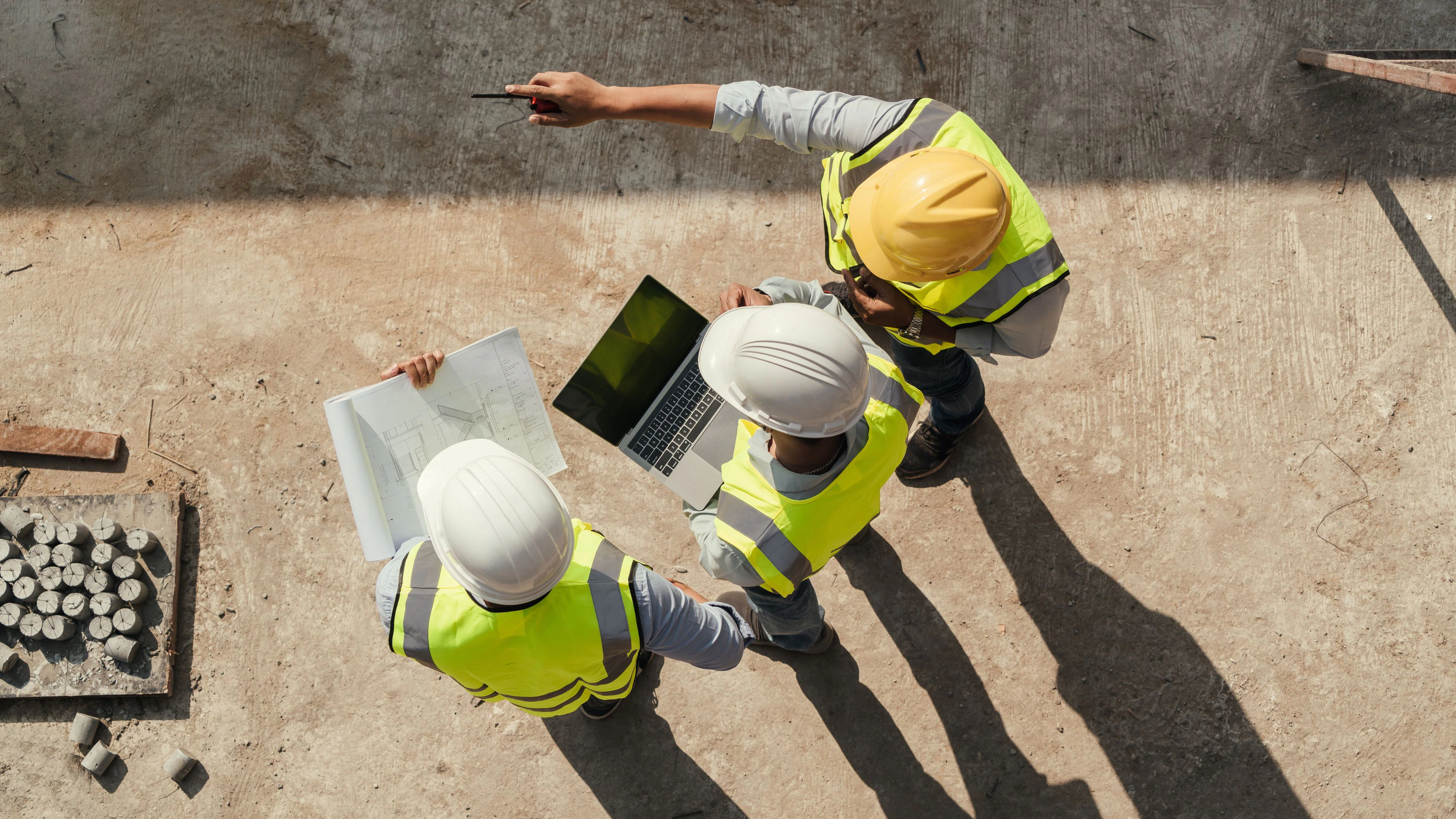 Top view, Team engineer building inspection use tablet computer and blueprint working at construction site. Civil Engineer, Contractor and Architect discussing in construction site.