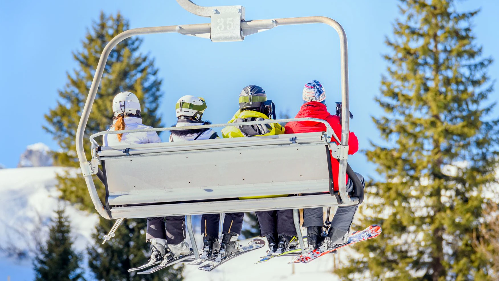 Skiers going up the mountain on a chairlift on a sunny winter day