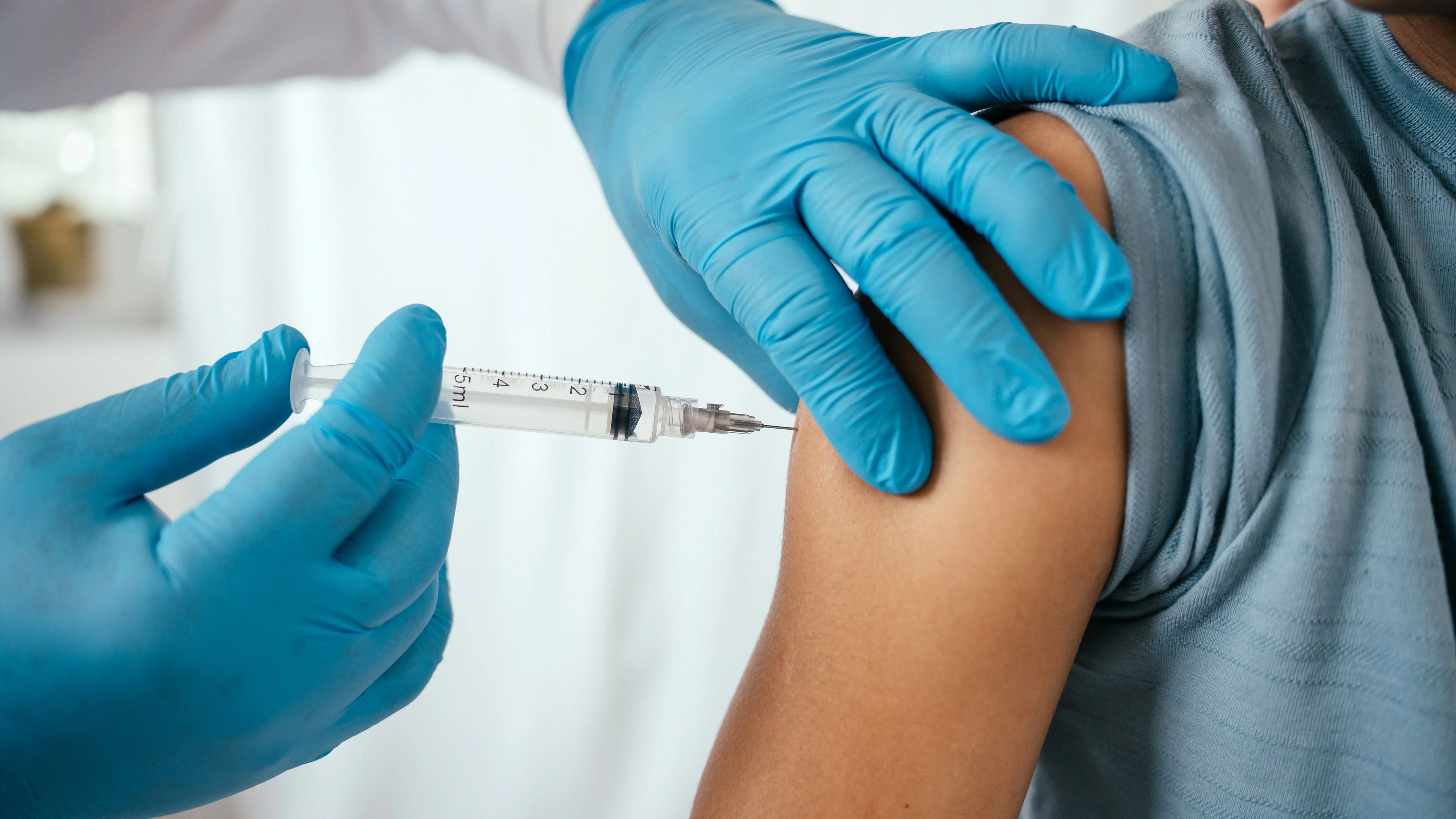 Doctor administering vaccine to teenager in doctor's office