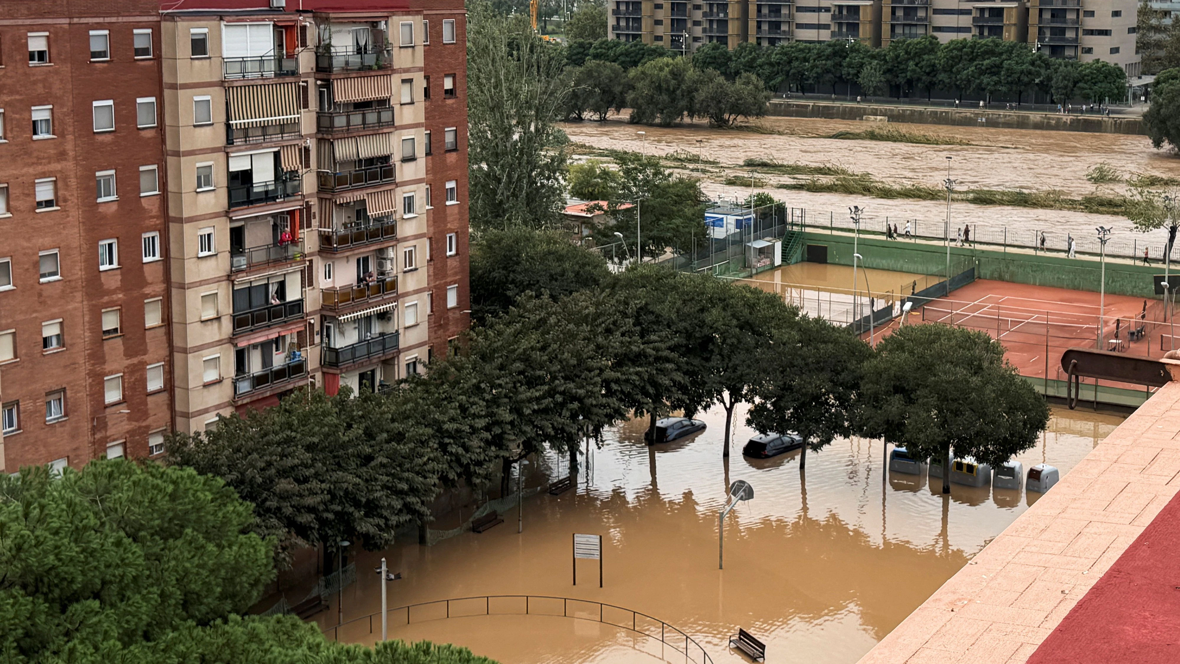 People look out from their balconies at the flooded playground near the Besos river following heavy rain, as Spain's meteorological agency AEMET issued a red alert for Catalonia, in Sant Adria de Besos, on the outskirts of Barcelona, Spain, October 4, 2026. REUTERS/Horaci Garcia 