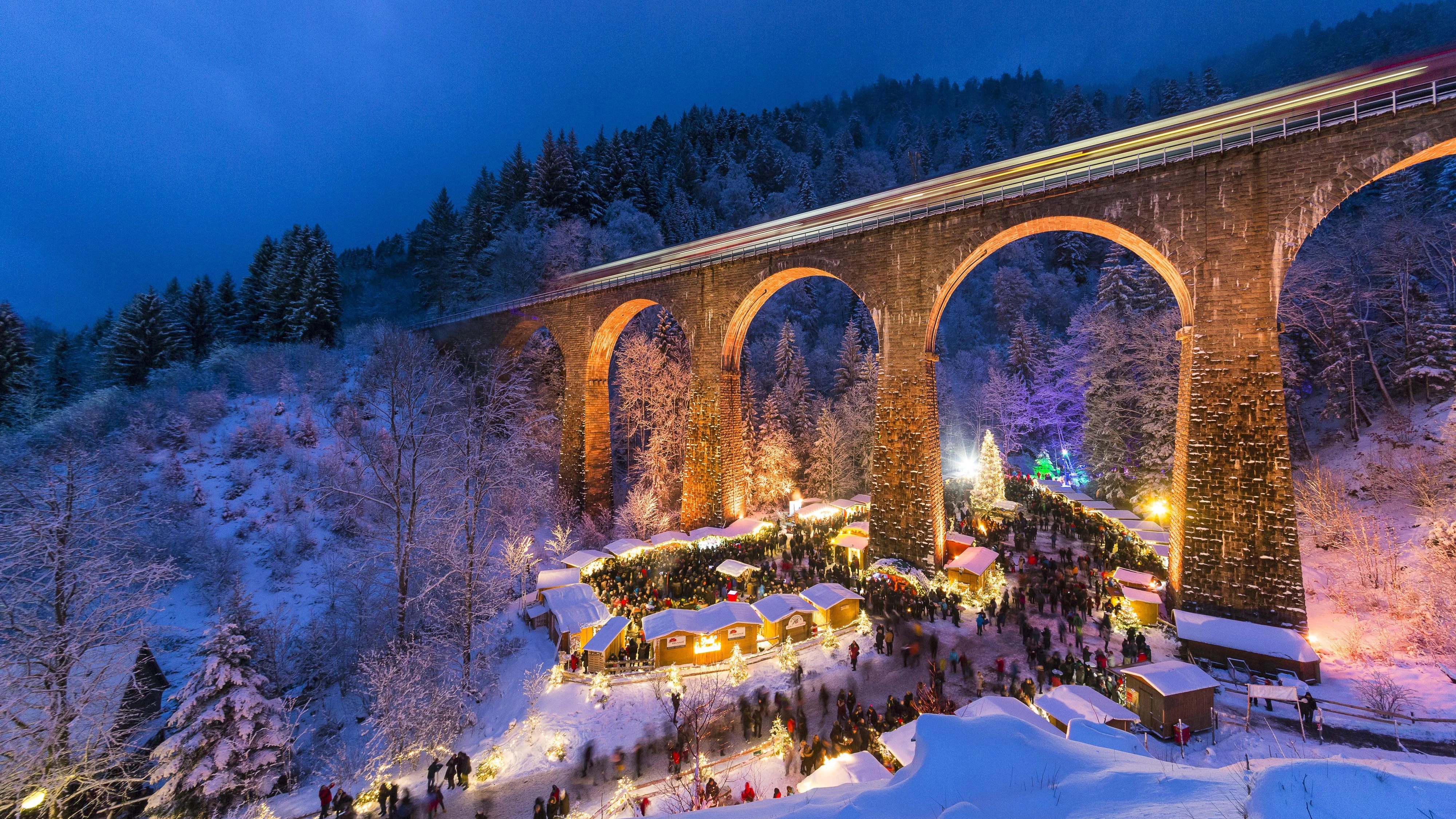 Weihnachtsmarkt in der Ravennaschlucht im verschneiten Hochschwarzwald, das Eisenbahn Viadukt der Höllentalbahn ist farbig angestrahlt, Schwarzwald, Breitnau, Baden-Württemberg, Deutschland, Europa