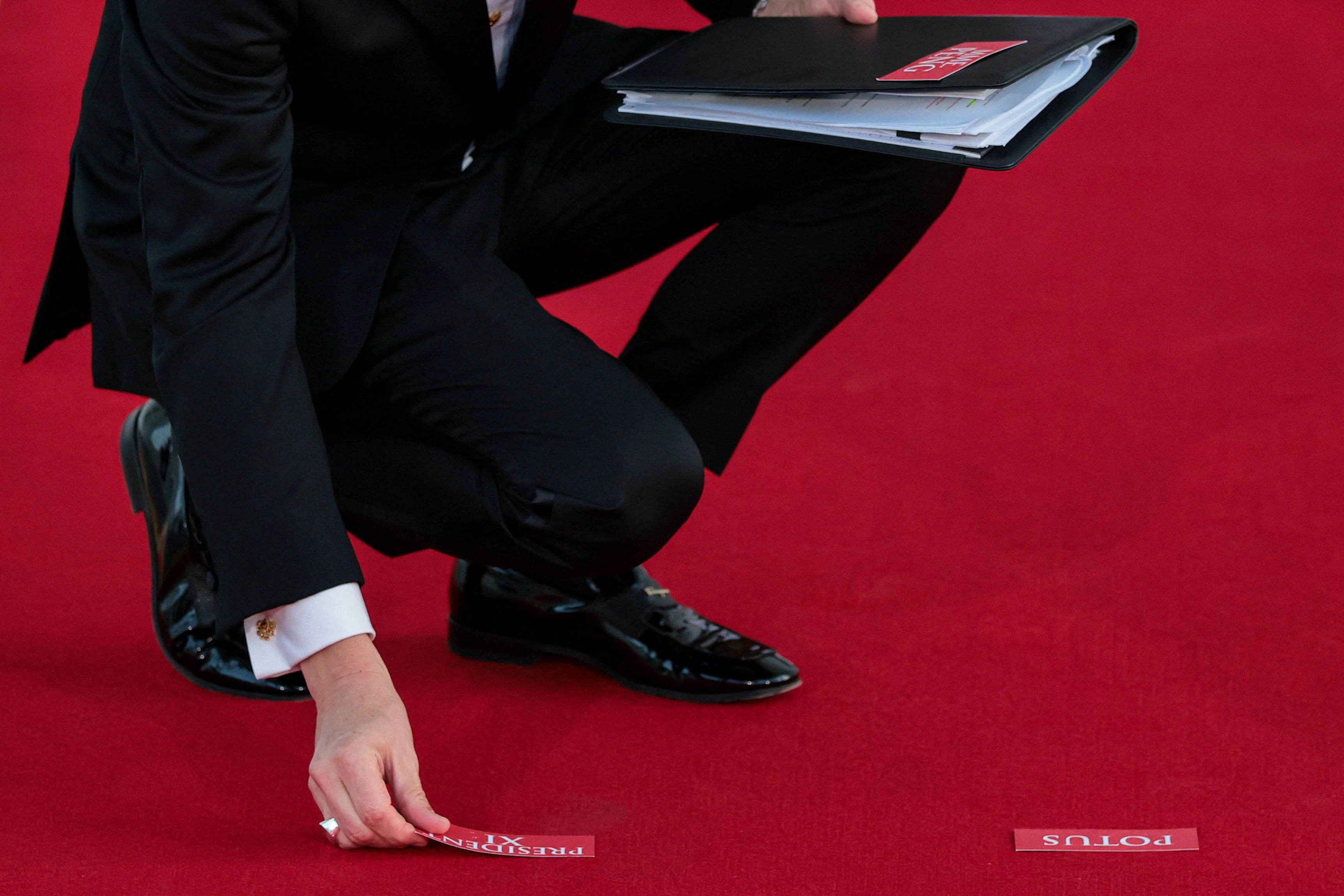 Ein Mitarbeiter klebt Markierungen auf den Roten Teppich: Der Ablauf des Besuchs wurde auch danach zusammengestellt, wie lange Präsident Xi gehen oder stehen musste