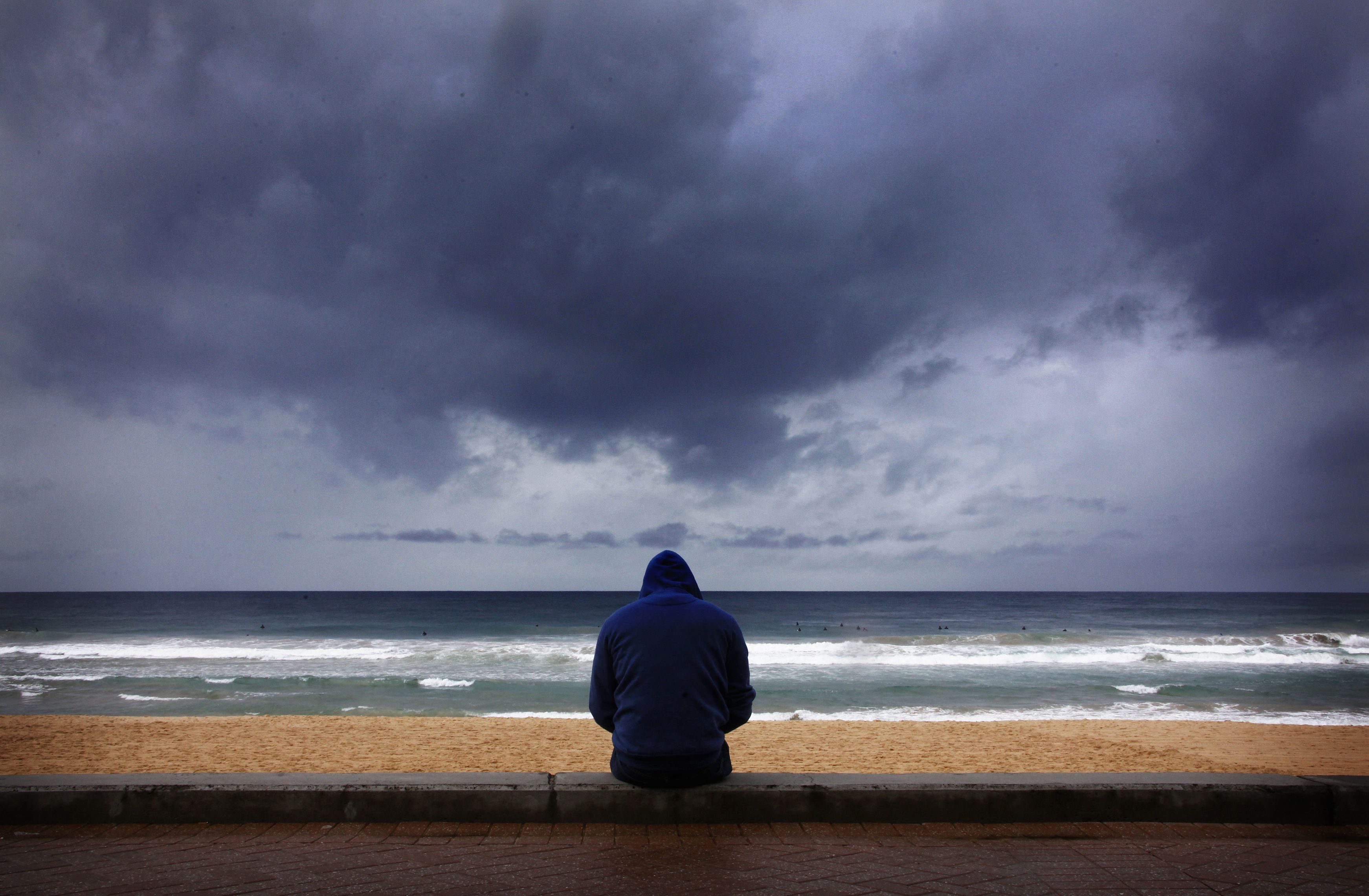 Ein Surfer beobachtet die Wellen, während sich Sturmwolken vom Pazifik her zusammenziehen 