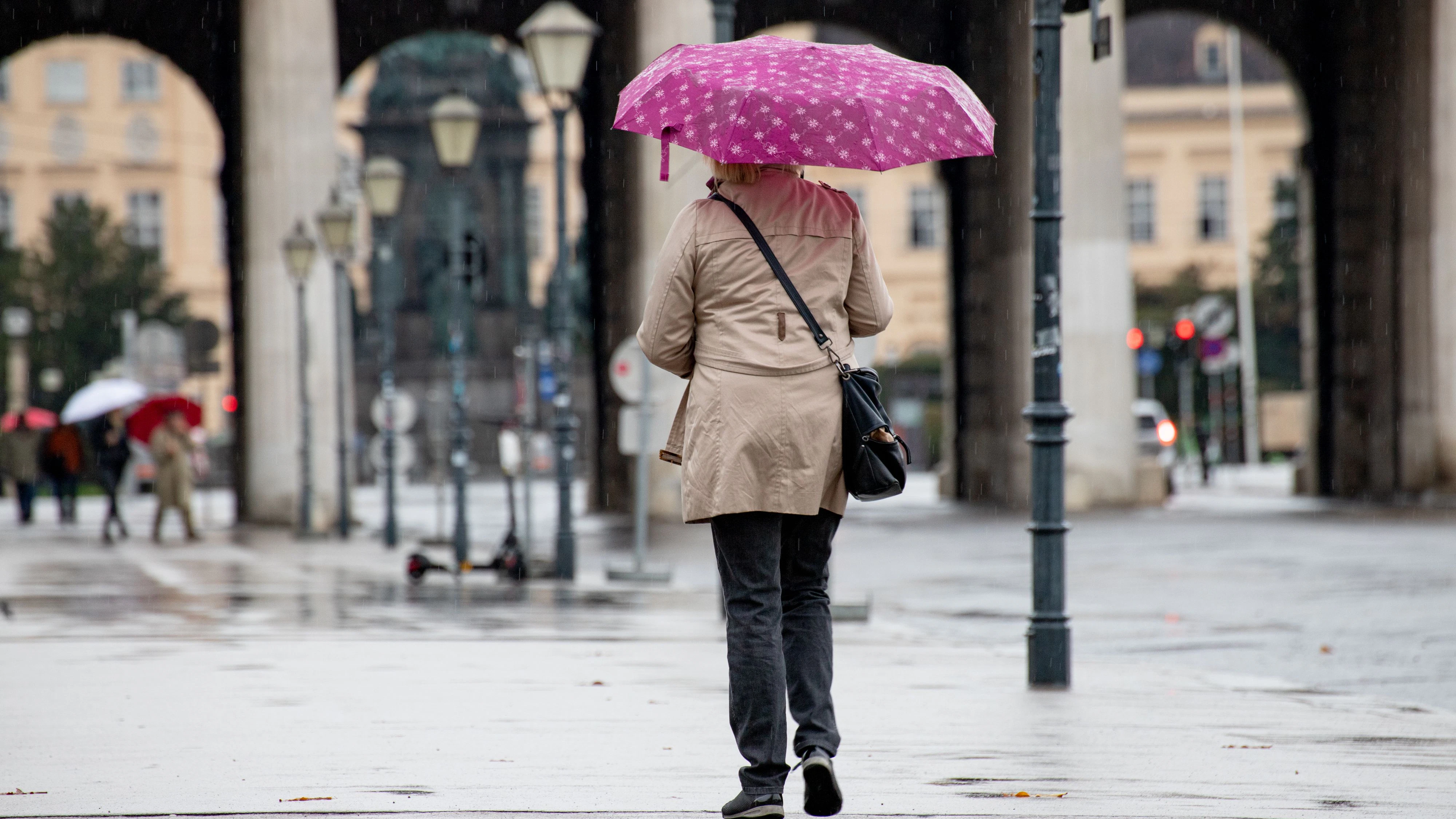 Das Wetter zeigt sich kalt und regnerisch im Herbst in Wien. Im Bild: Frau mit Regenschirm spaziert am Wiener Heldenplatz. Oktober 2020 // Autumn: Rainy and cold weather conditions in Vienna. Picture: Woman with an umbrella walks in Vienna, Austria. October 2020
