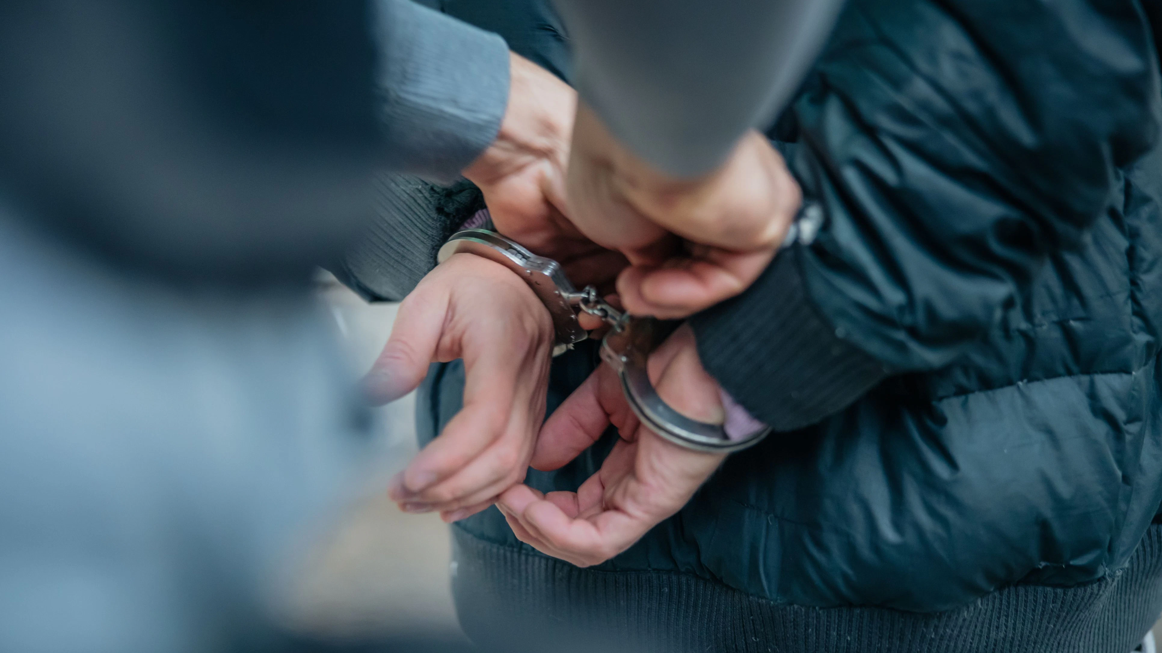 Policeman unlocking a handcuffs on the criminal's back.