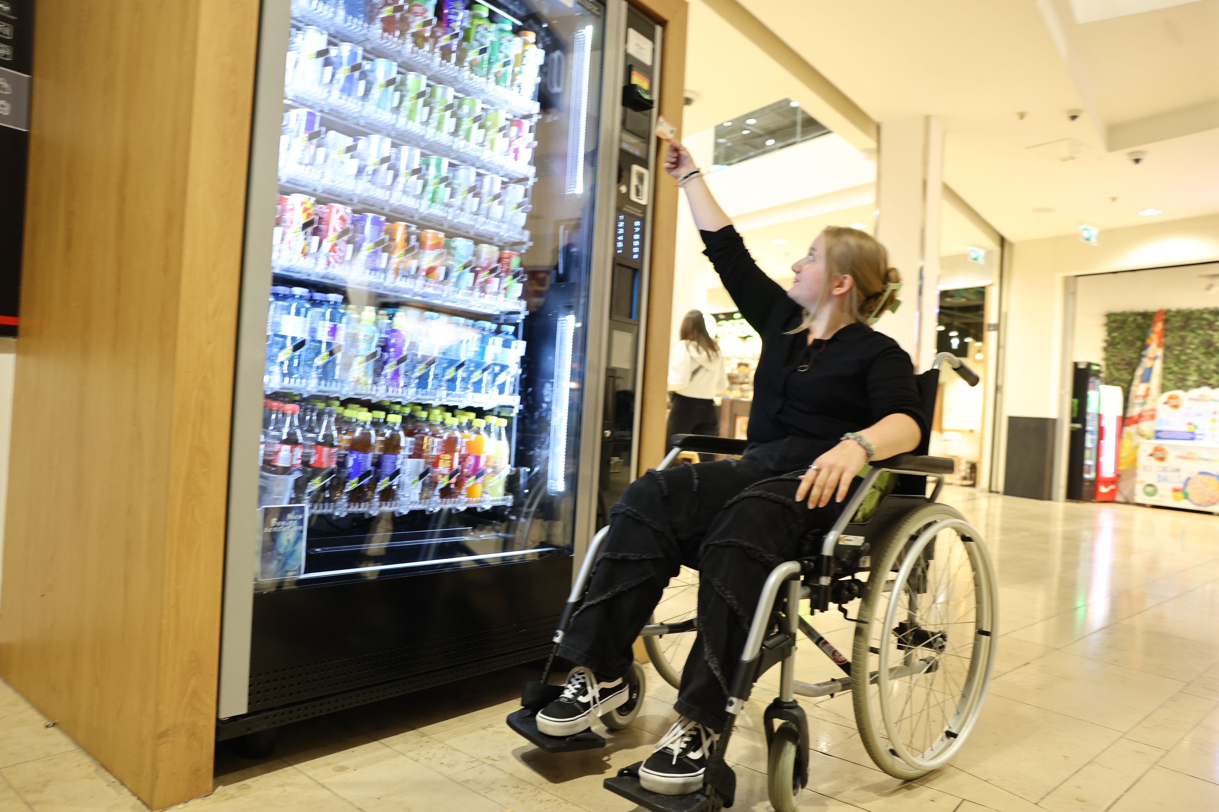 Valerie sitzt erstmals im Rollstuhl, den Automaten kann sie nicht alleine bedienen: Das Geldfach ist zu hoch!