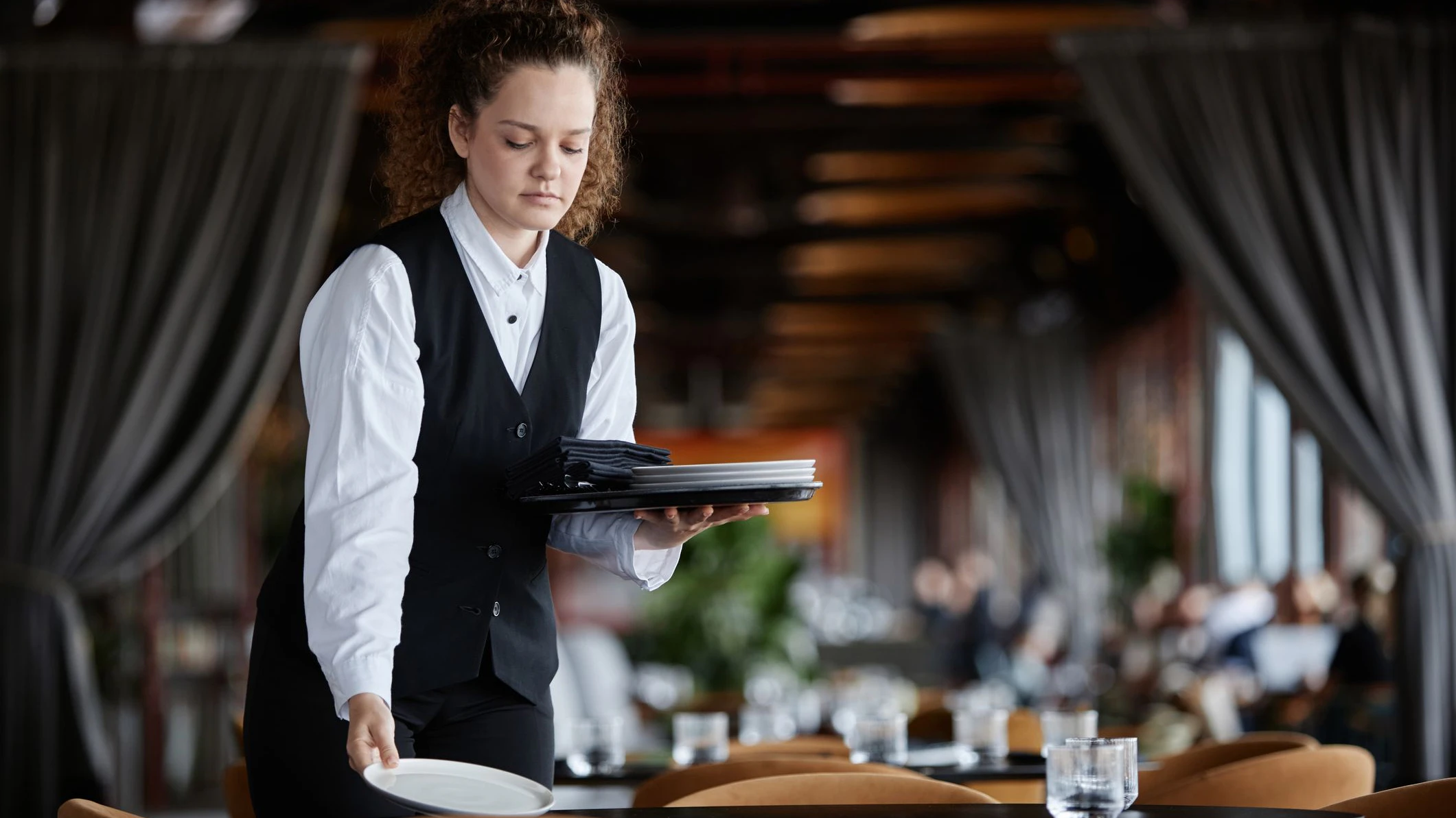 Waist up portrait of young woman as female server setting table in luxury restaurant preparing for opening, copy space
