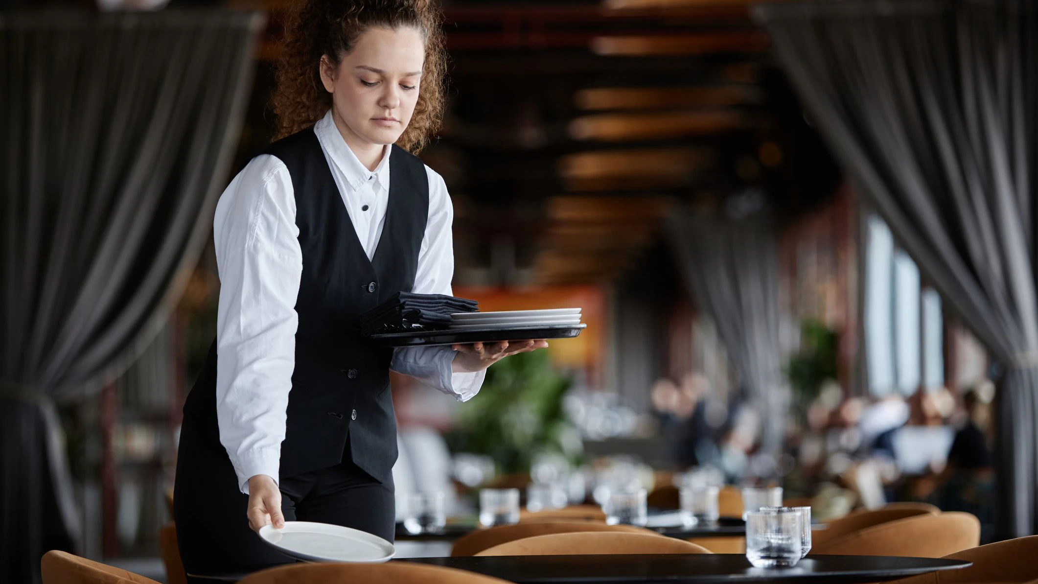 Waist up portrait of young woman as female server setting table in luxury restaurant preparing for opening, copy space