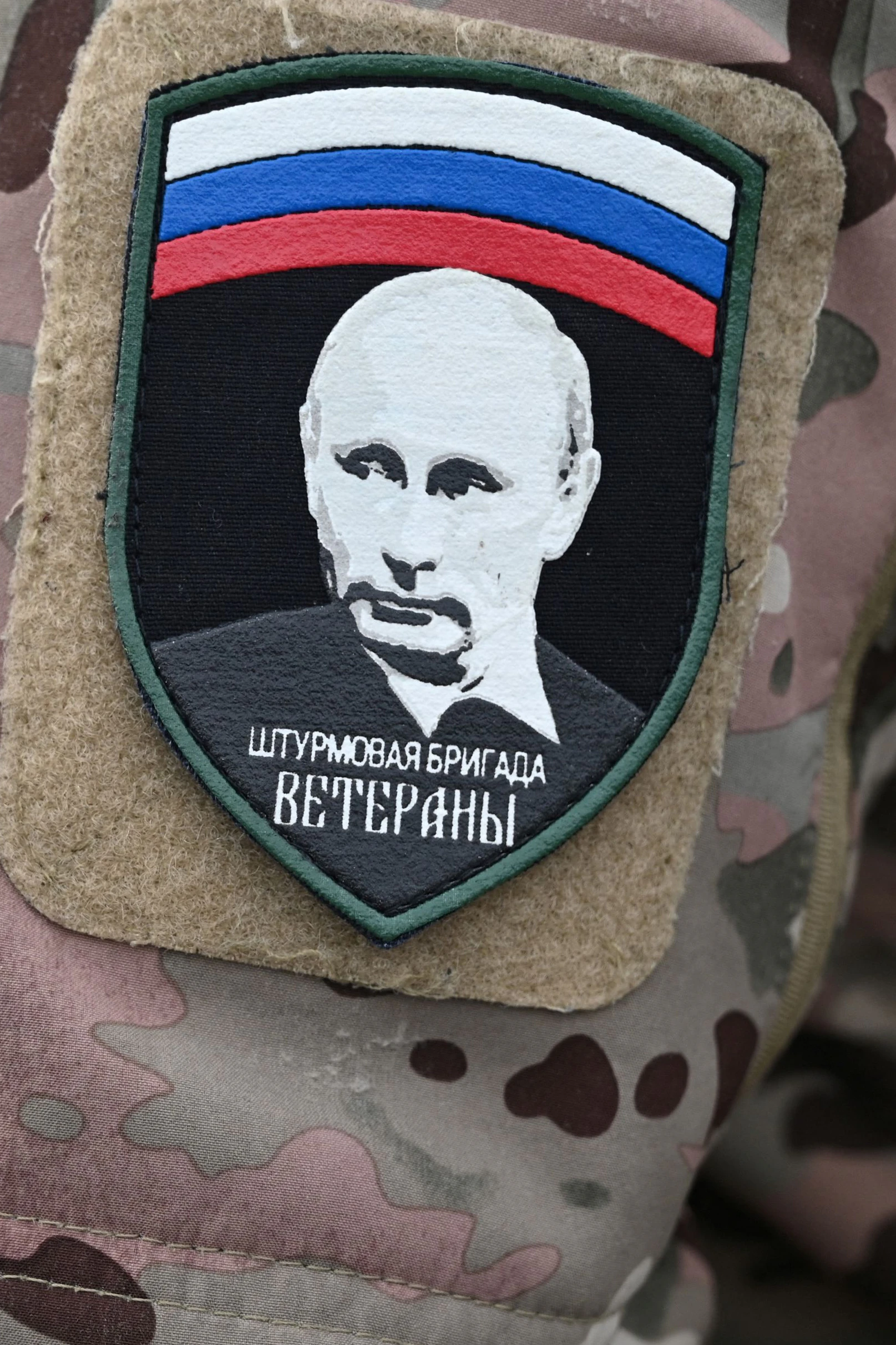 Ein russischer Soldat trägt einen Aufänger an seiner Uniform, der Text bedeutet "Veteranen-Sturmbrigade". Tausende junge Männer verlassen indes ihr Land, um der Einberufung zu entgehen