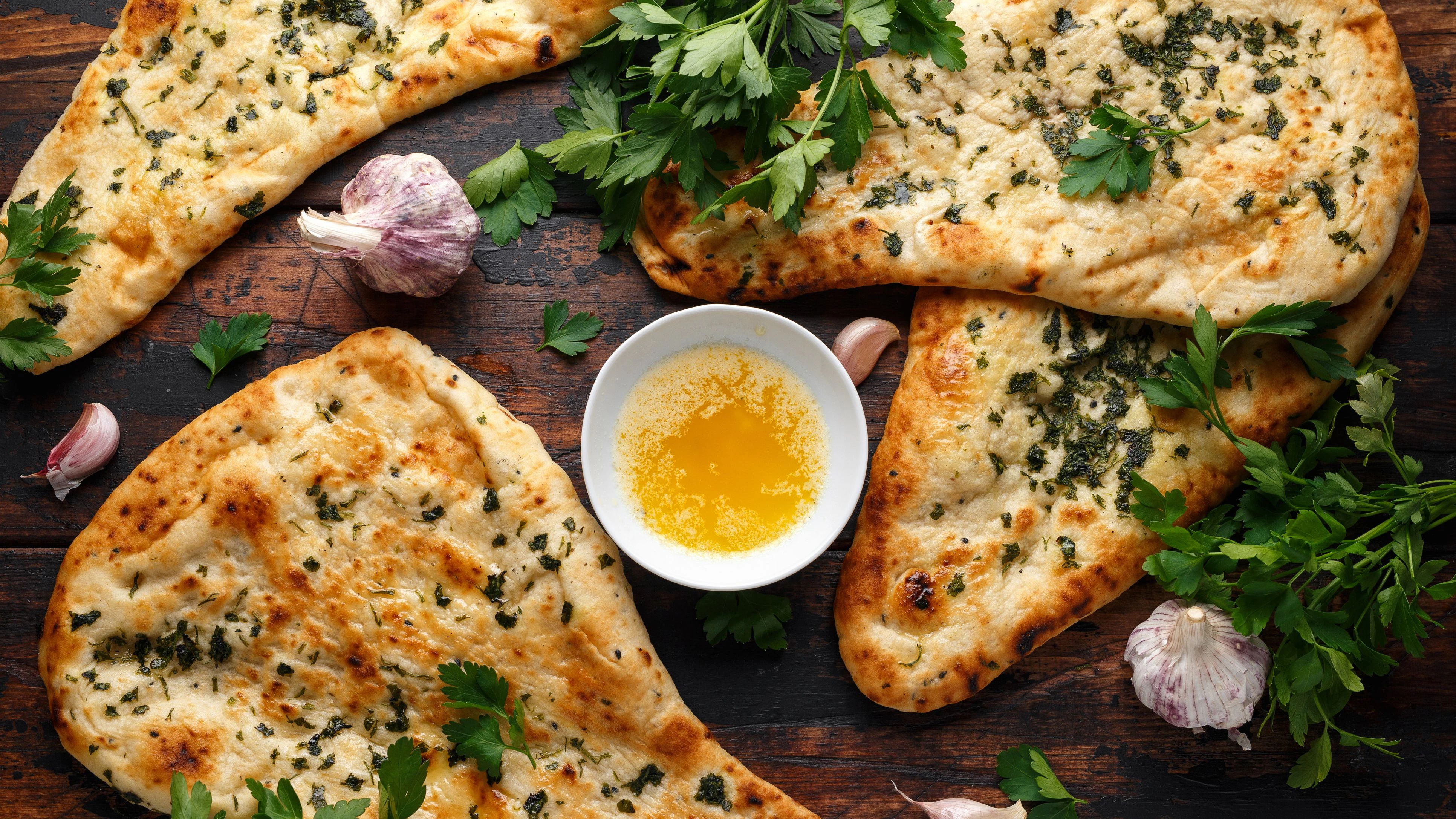 Indian naan bread with garlic butter on wooden table.