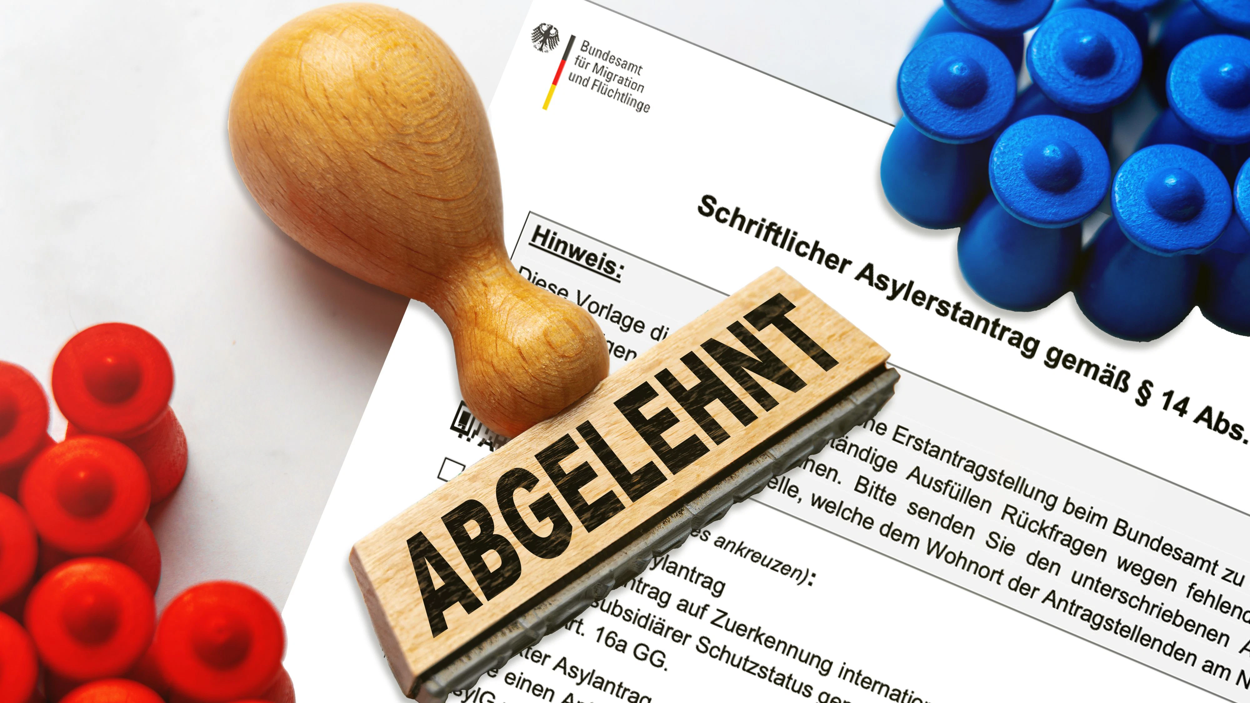 FOTOMONTAGE, ein Stempel mit der Aufschrift ABGELEHNT liegt auf einem schriftlichen Asylantrag des Bundesamts für Migration und Flüchtlinge. Das Bild symbolisiert die Ablehnung eines Asylantrags und mögliche Konsequenzen für den Antragsteller.