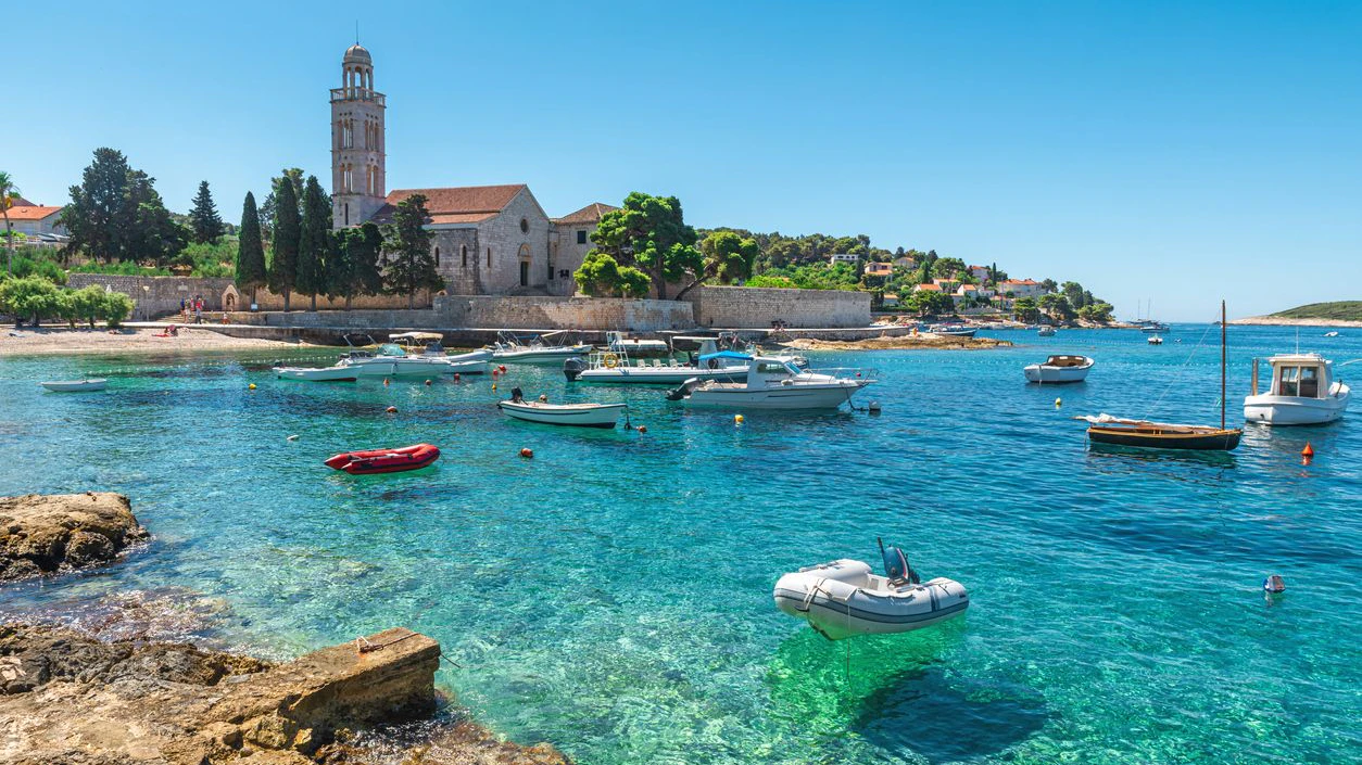 Turquoise water of Adriatic sea bay on Hvar island with franciscian monastery and boats in Dalmatia region, Croatia. Summer vacation destination