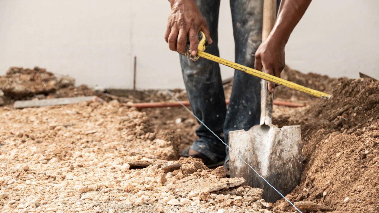 Man measuring and digging a hole in the ground with shovel