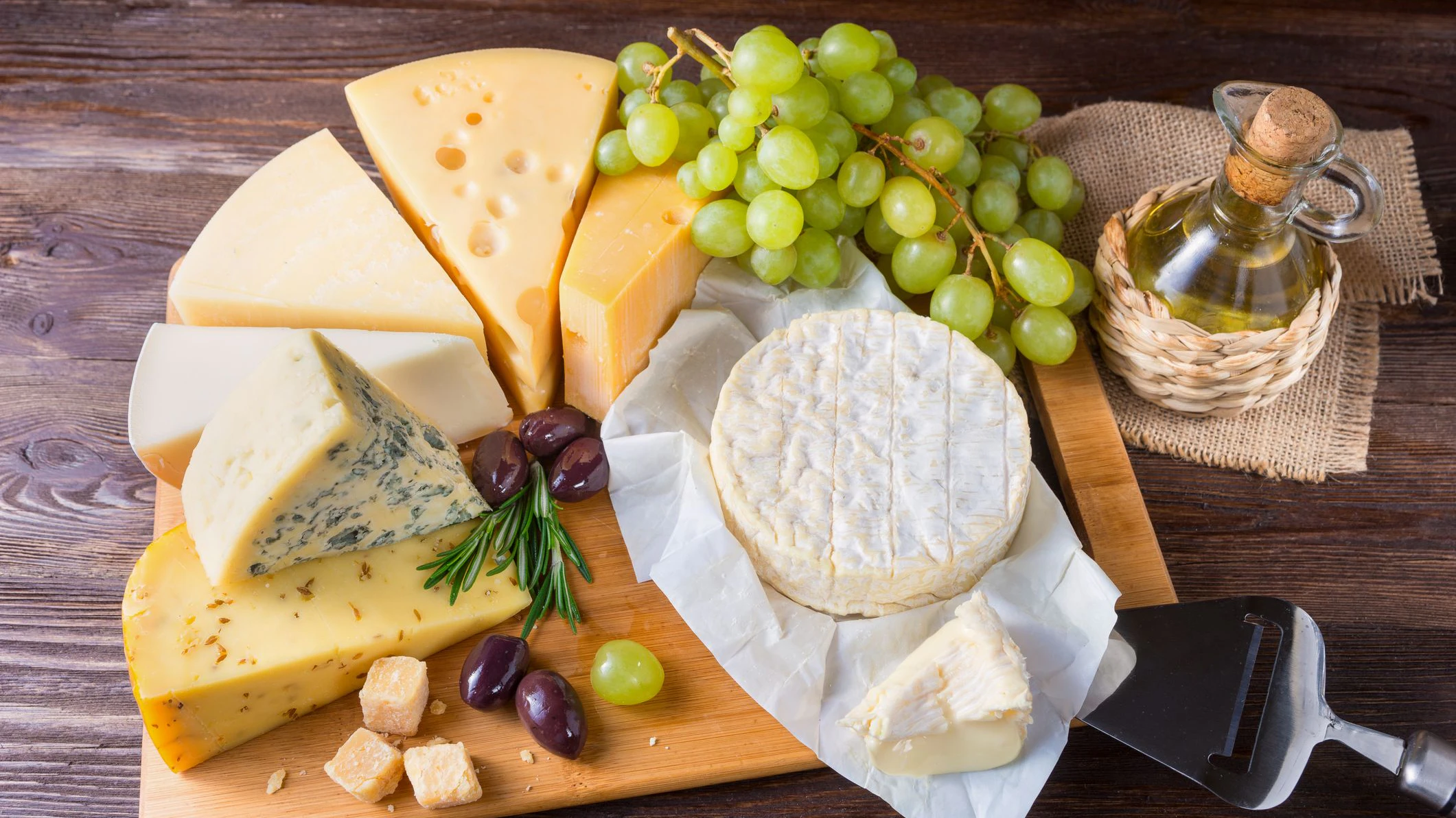 Tasting cheese dish on a wooden board. Food for wine and romantic, cheese delicatessen on a dark wooden table. Copy space