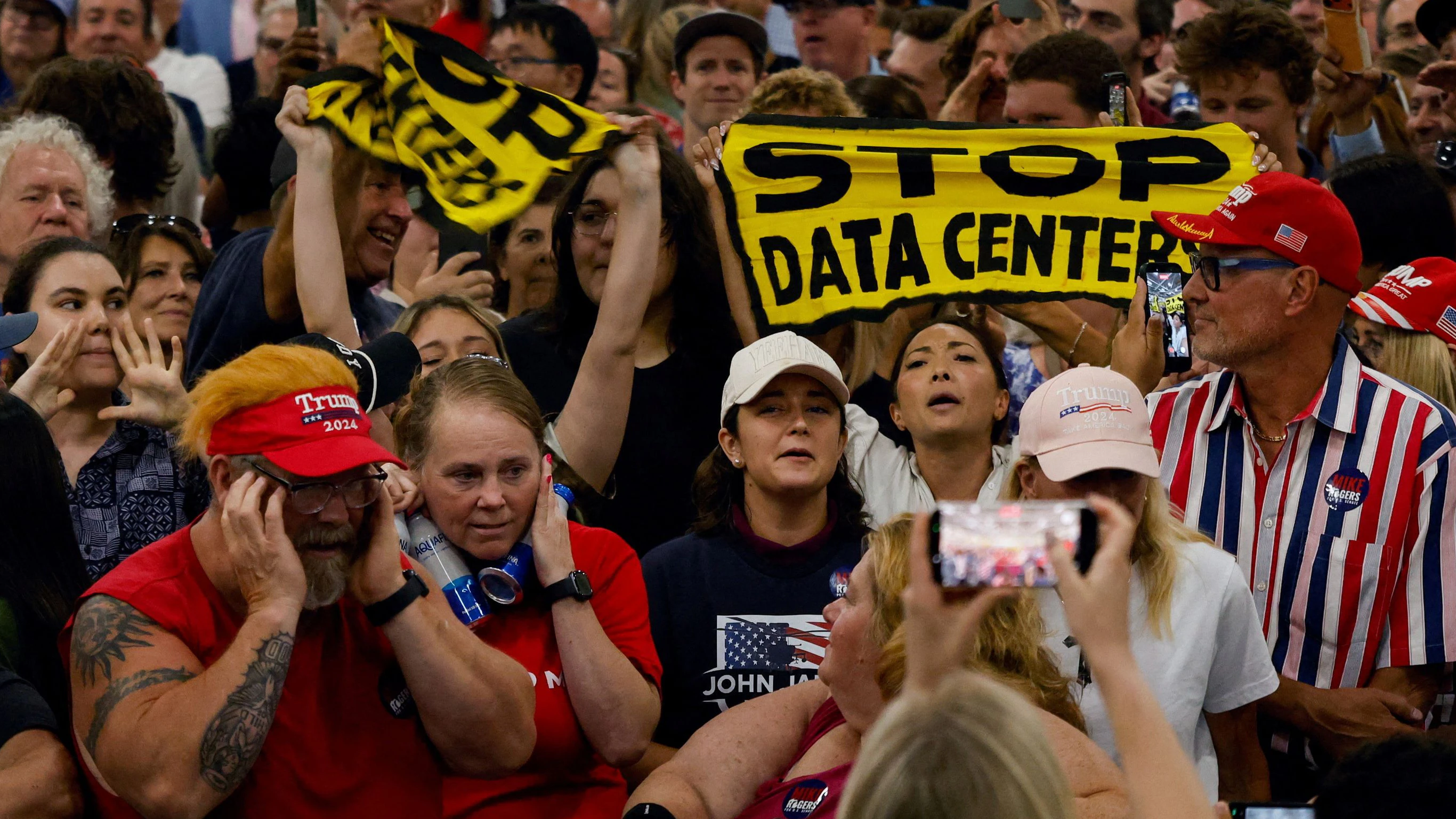 Protestors hold up 'Stop data centers' signs, on the day of U.S. President Donald Trump's speech at the General Motors Proving Ground, in Milford, Michigan, U.S. July 27, 2026.  REUTERS/Carlos Osorio     TPX IMAGES OF THE DAY     