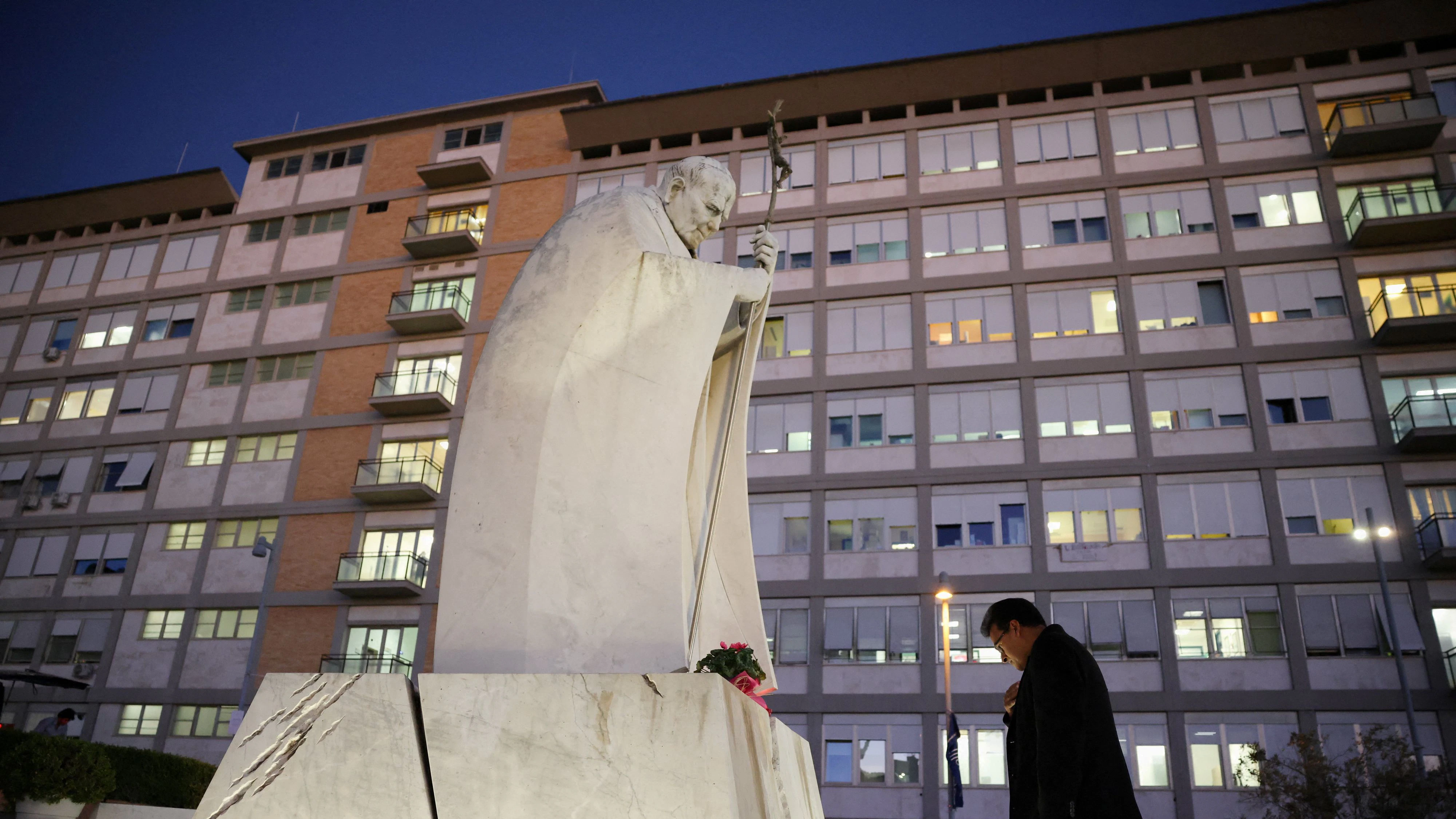 A man prays before the statue of the late Pope John Paul II outside Gemelli Hospital, where Pope Leo is hospitalised to undergo surgery to remove a lung nodule, in Rome, Italy, October 13, 2026. REUTERS/Stoyan Nenov  REFILE - CORRECTING FROM "AHEAD OF SURGERY" TO "TO UNDERGO SURGERY".