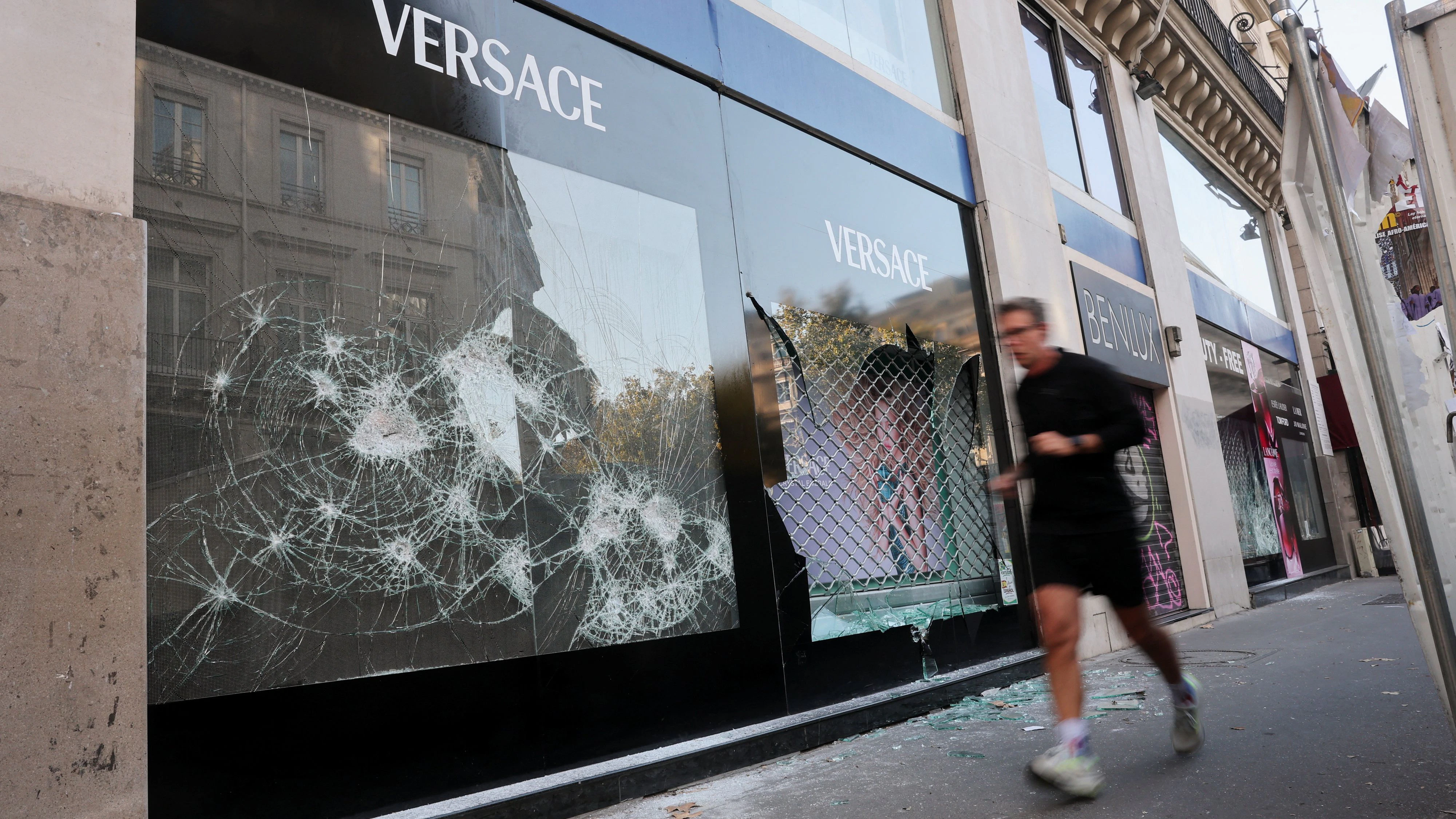A man passes by vandalised Versace and Benlux stores, the day after clashes during a national day of demonstrations against the cost of living and rising fuel prices, in Paris, France, October 18, 2026. REUTERS/Stephanie Lecocq