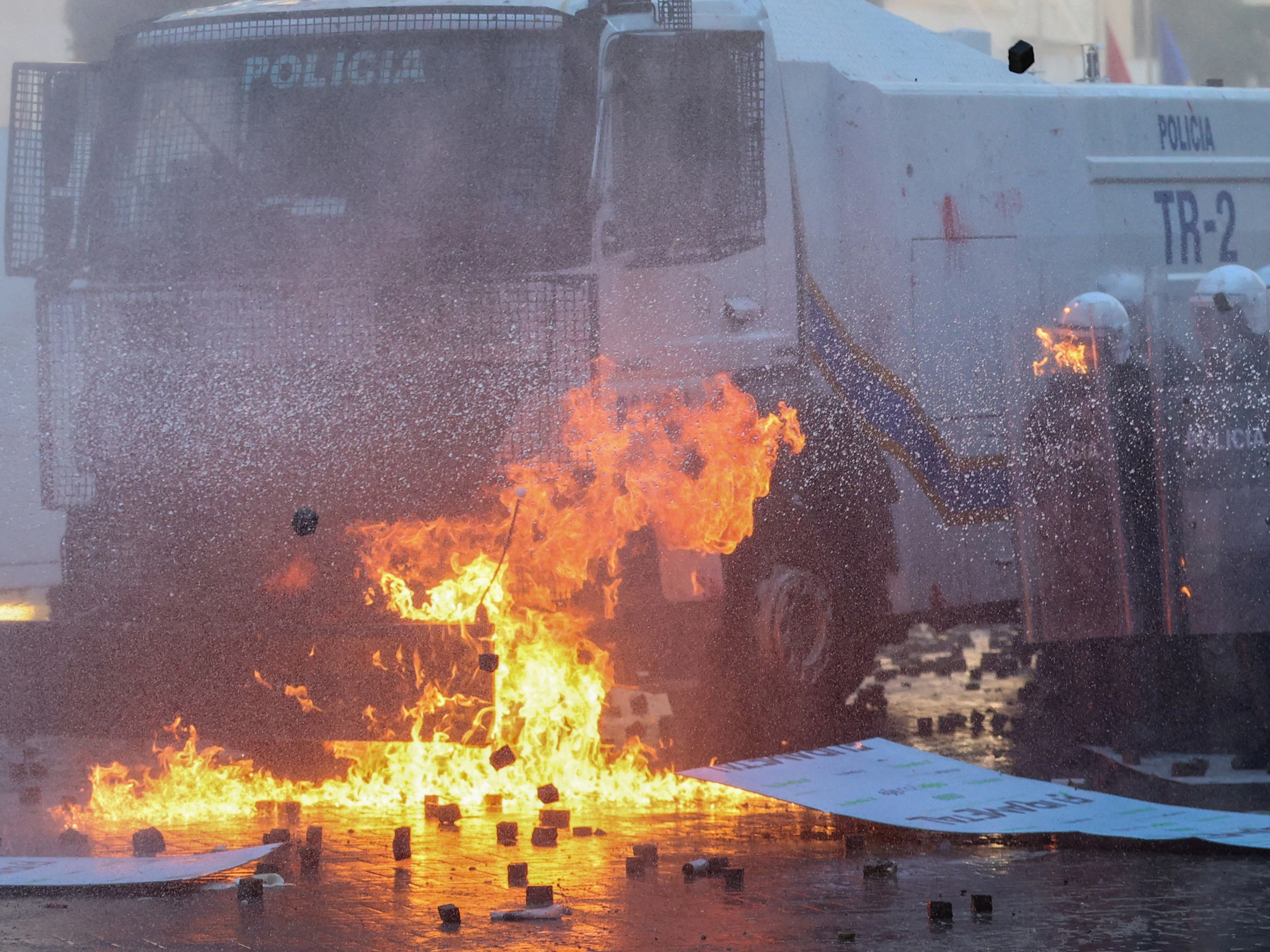 Ein Wasserwerfer der Polizei vor brennenden Flüssigkeiten und Pflastersteinen in der albanischen Hauptstadt Tirana am Samstag, 17. Oktober.