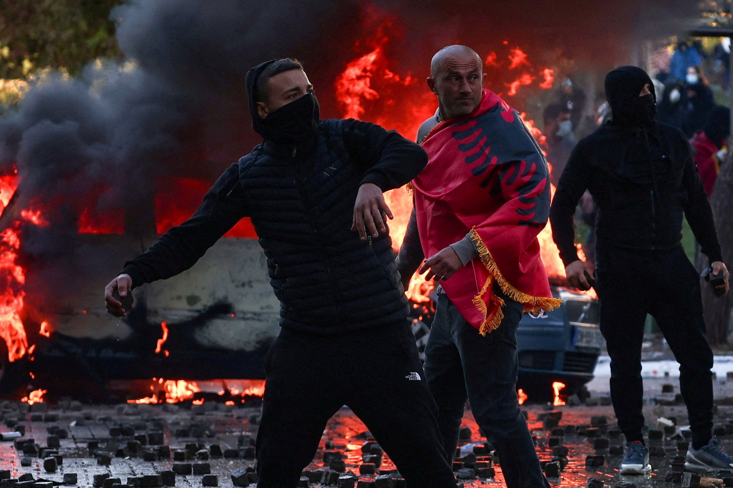 Ein Demonstrant mit einer albanischen Nationalflagge beobachtet die Zusammenstöße zwischen Protestierenden und der Polizei bei einer von Studenten organisierten Demonstration gegen die Regierung in Tirana, Albanien, am 17. Oktober 2026.