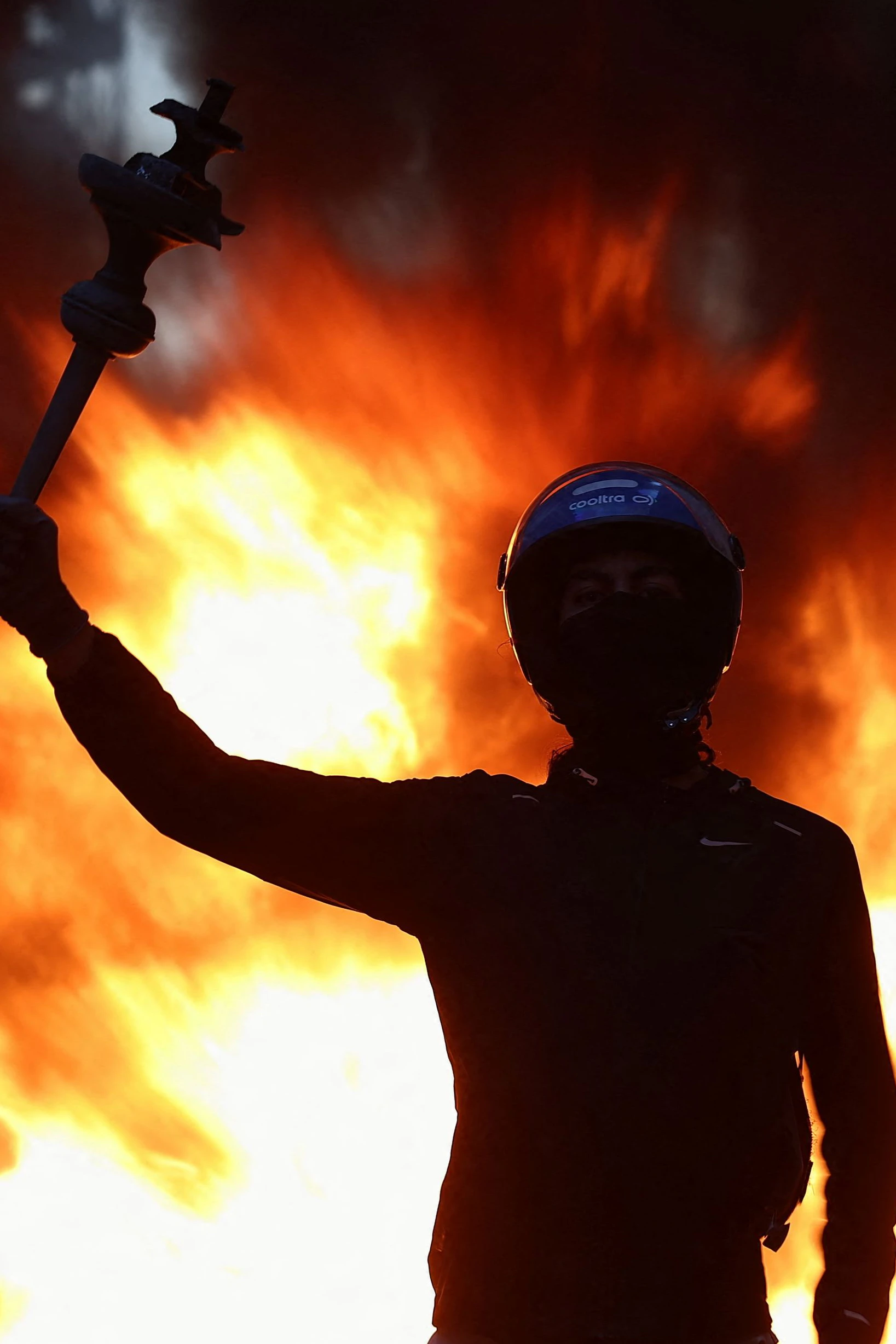 Ein Demonstrant reckt ein Beutestück zum Himmel, hinter ihm brennen Barrikaden: Frankreich erlebte ein Wochenende voller Gewalt, Zerstörung und Ausschreitungen