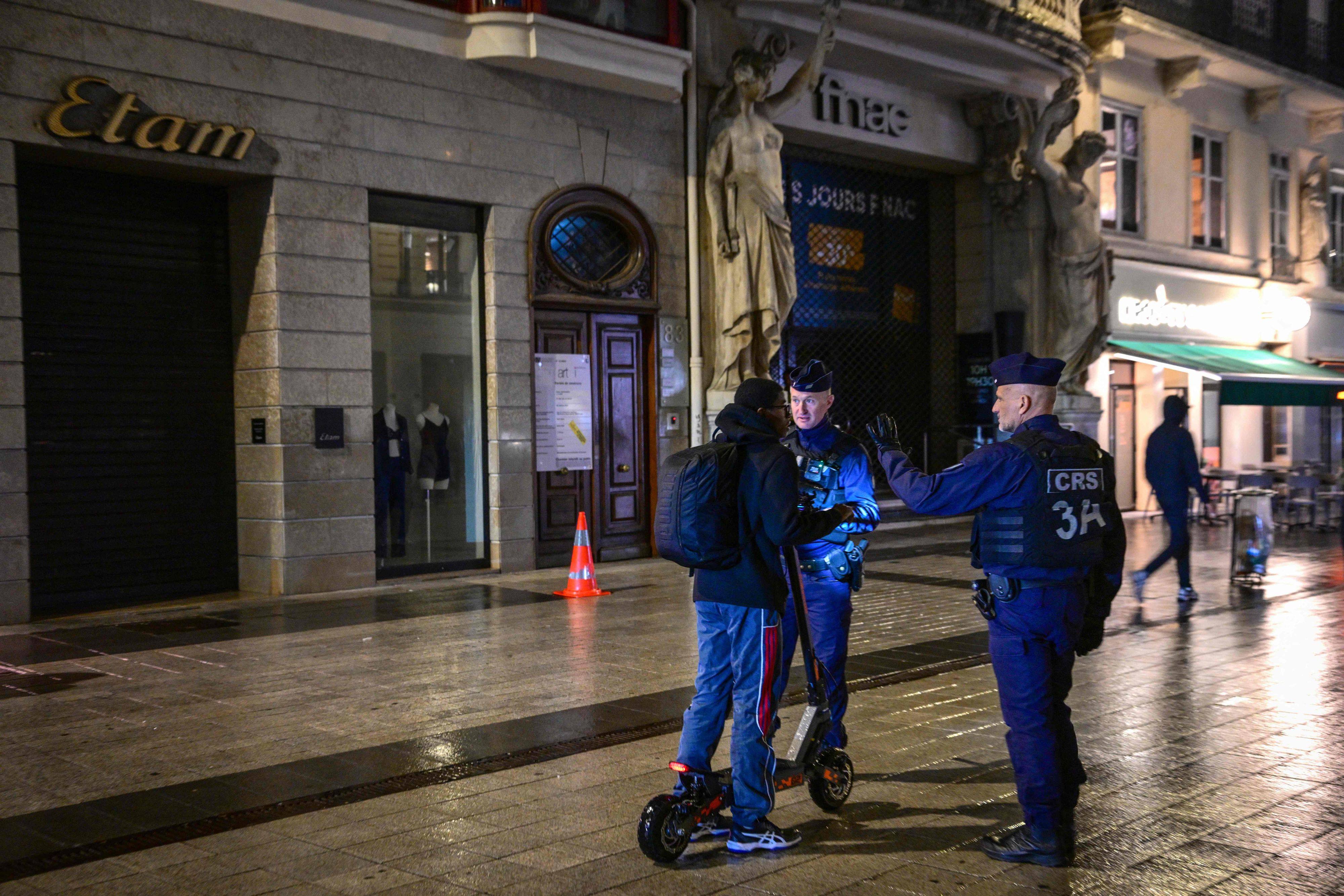 Französische Polizeibeamte kontrollieren am 19. Oktober 2026 in Lyon eine Person während einer nächtlichen Teil-Ausgangssperre.