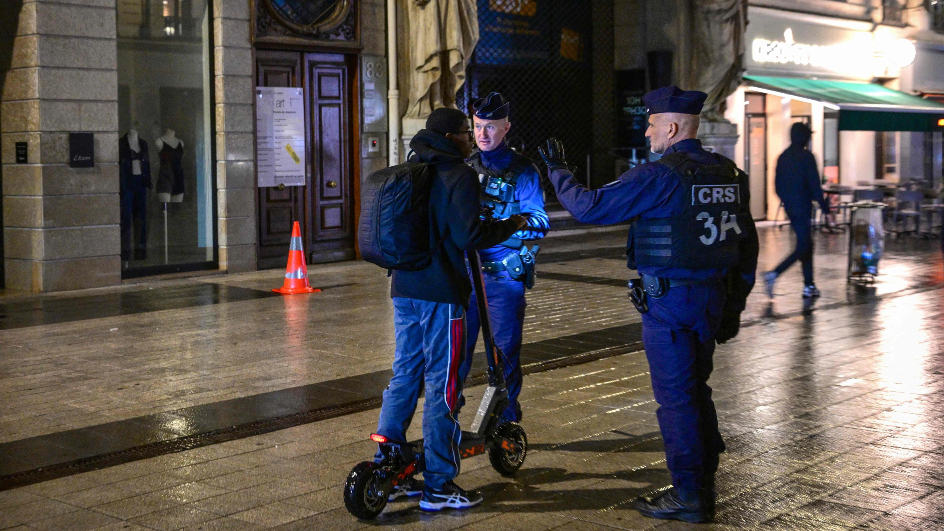 French police officers check a person during a partial curfew in Lyon on October 19, 2026, following weekend demonstrations over soaring prices degenerated into some of the worst street violence in recent years. France announced partial curfews in Paris and other cities that would be enforced from October 19 evening to October 20 morning in a number of cities including Paris, Lille and Lyon, to protect businesses. (Photo by OLIVIER CHASSIGNOLE / AFP)