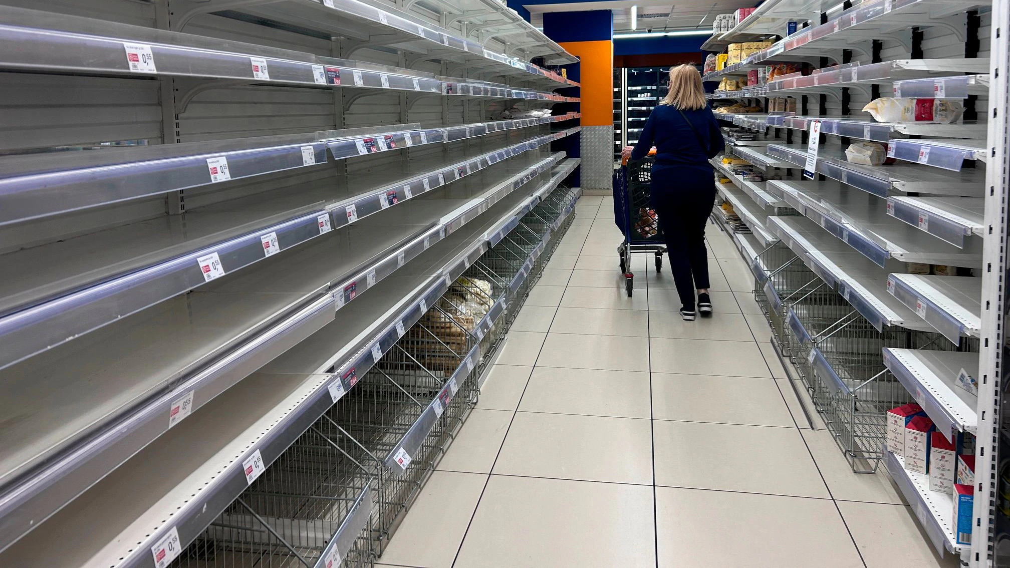 A woman walks past empty shelves at a supermarket in Naples, Italy, Tuesday, Oct. 20, 2026. (AP Photo/Alessandra Tarantino)
