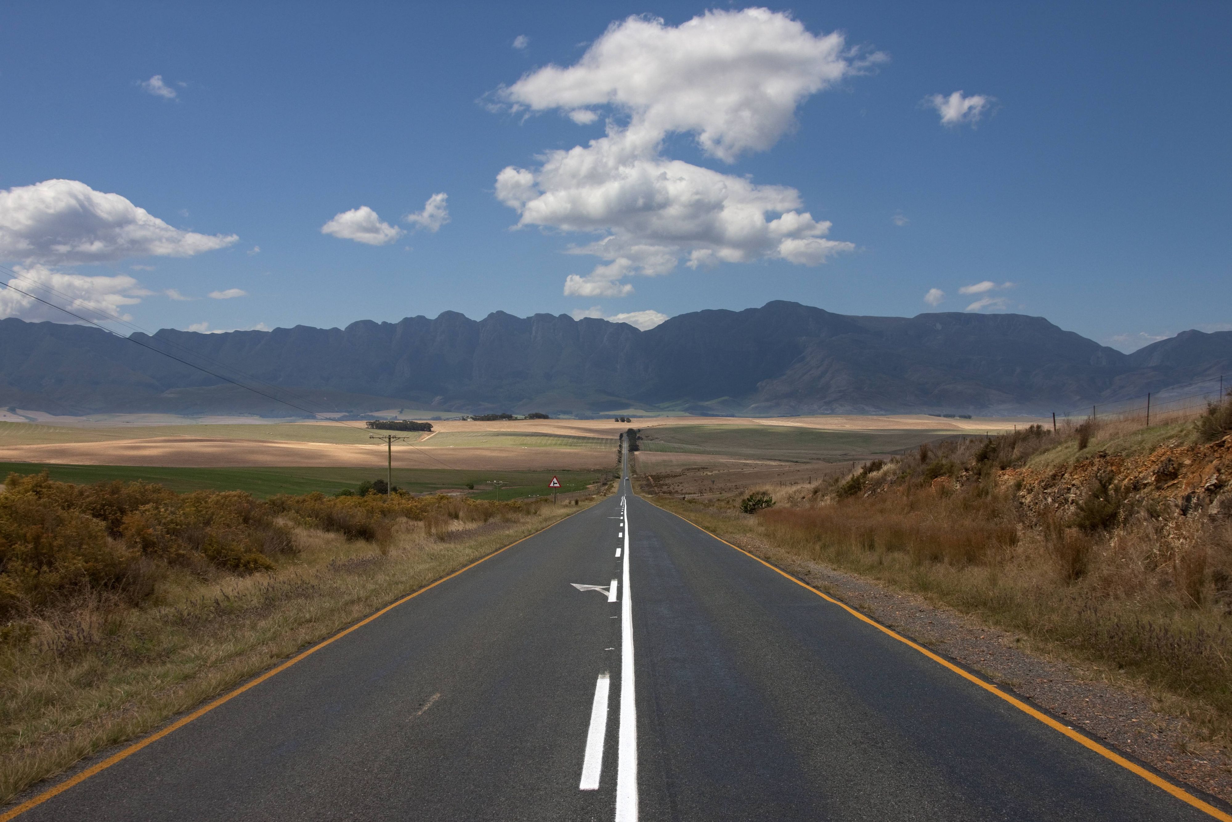 Blick auf eine leere Straße, die durch eine Landschaft führt, Swellendam, Provinz Westkap, Südafrika.