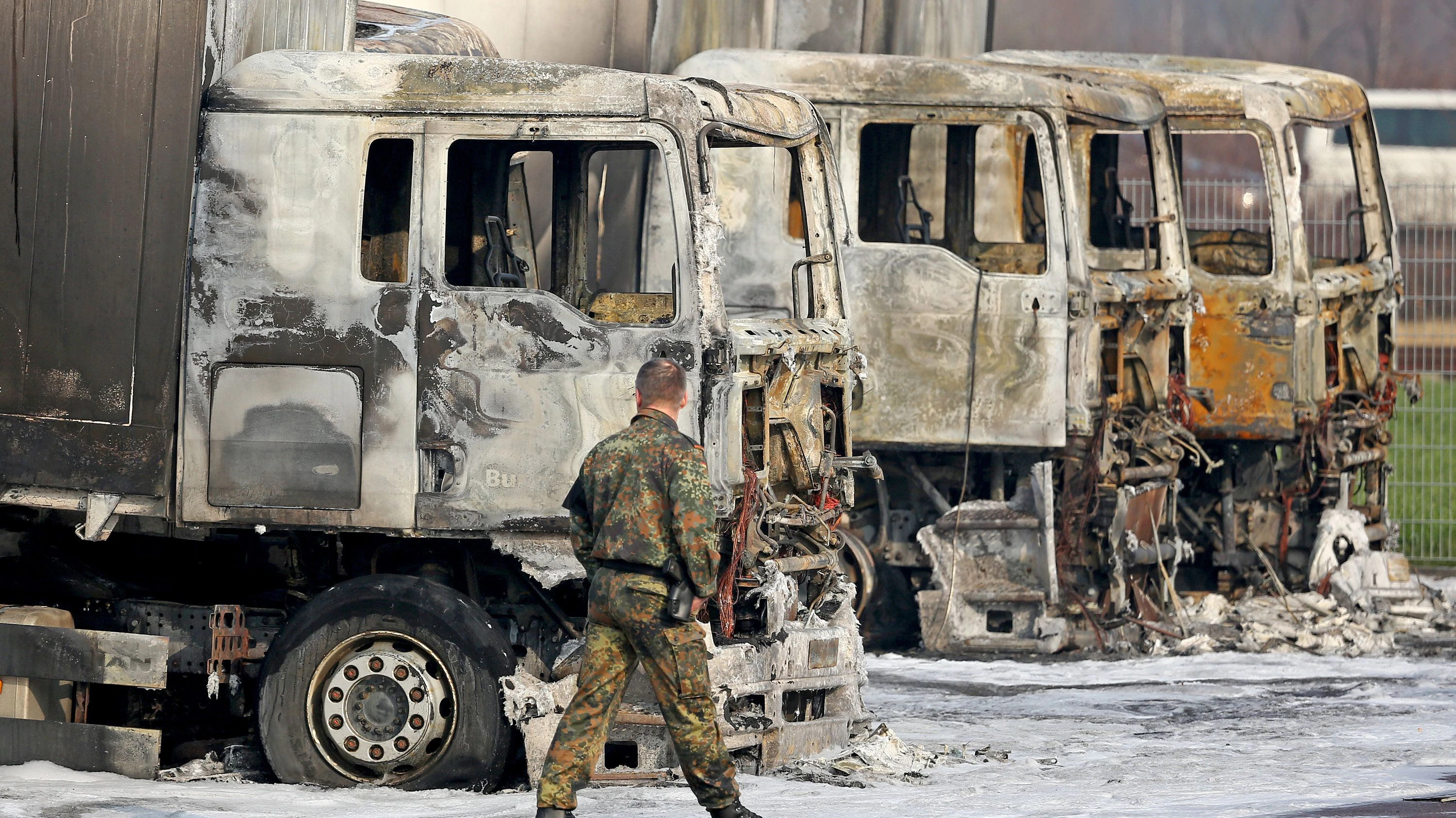 ABD0021_20160308 - Ein Feldjäger besichtigt mehrere ausgebrannte Lkw der Bundeswehr am 08.03.2016 in Leipzig (Sachsen). Unbekannte Brandstifter haben auf dem Werkstattgelände acht Lastwagen und zwei Anhänger angezündet - sechs dieser Fahrzeuge gehören der Bundeswehr. Sie wurden teilweise völlig zerstört. Zu Höhe des Schadens lagen zunächst keine Angaben vor. Foto: Jan Woitas/dpa +++(c) dpa - Bildfunk+++