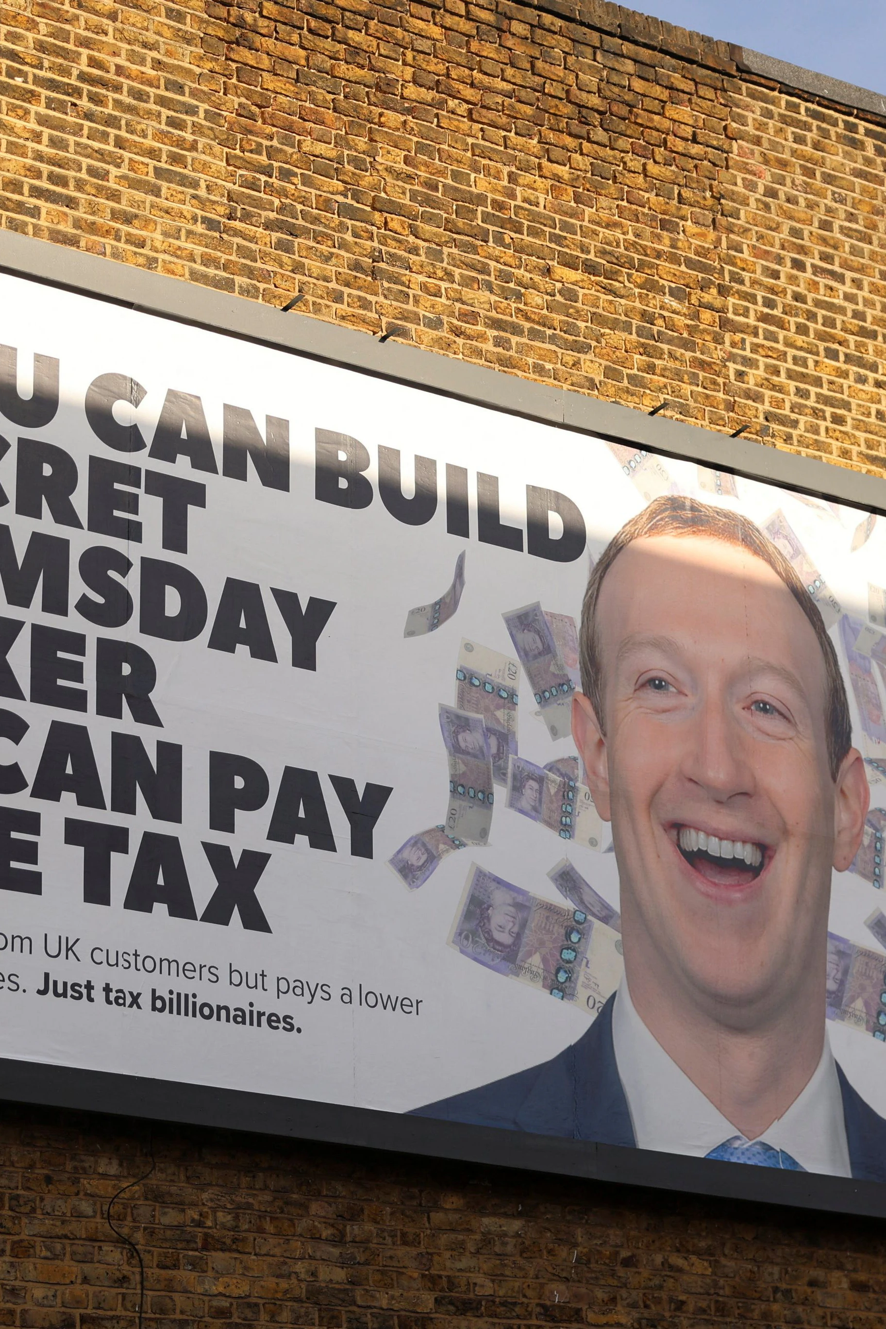 Das Plakat stammt zwar aus London, die Botschaft ist aber die gleiche: Multimilliardär und Meta-Gründer Mark Zuckerberg soll zur Kasse gebeten werden